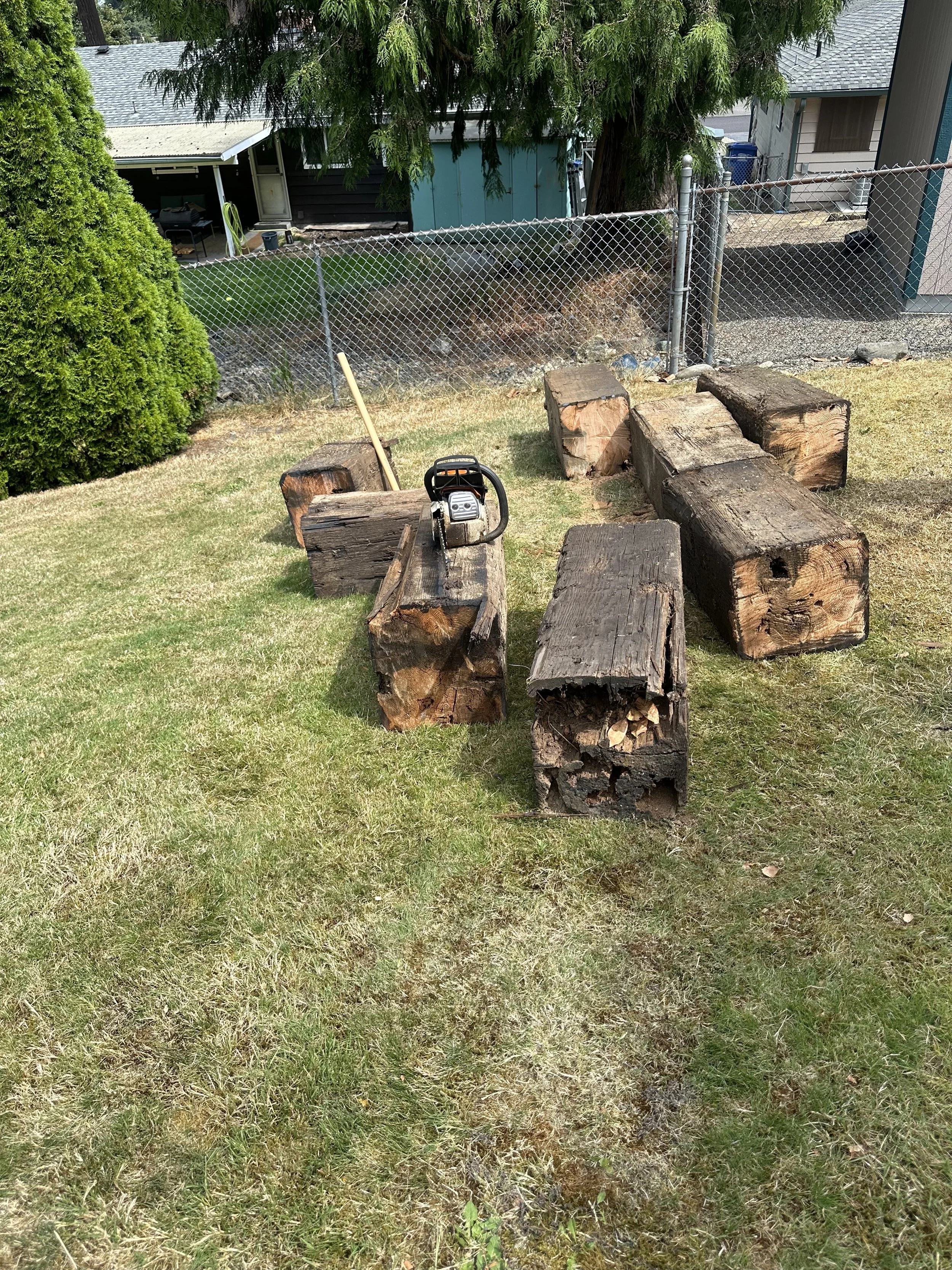 Progress — beams cut into sections with the chainsaw resting on one of the pieces.