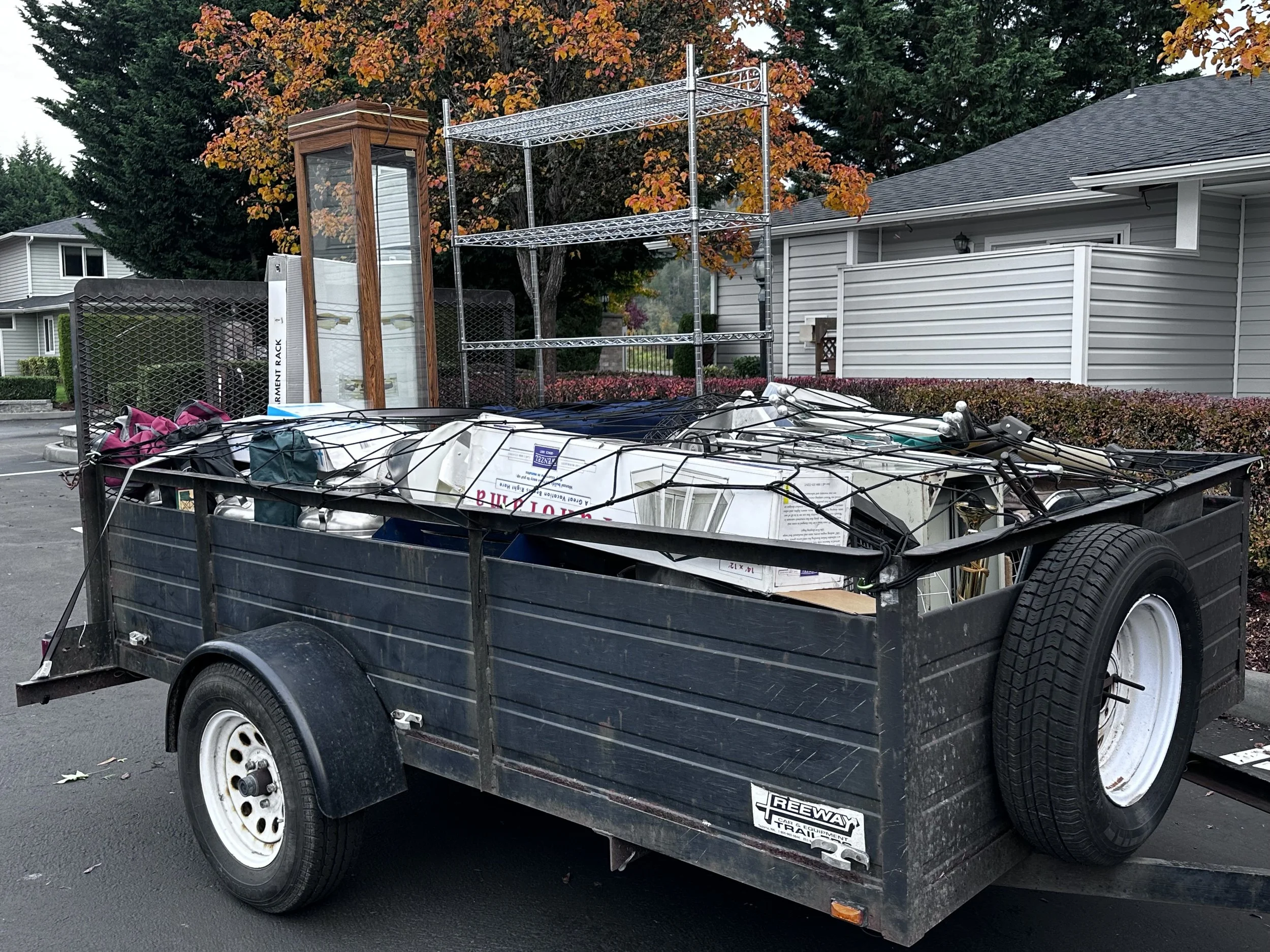 Side view of junk removal trailer packed with mixed household items, metal shelving, and debris in Puyallup, WA