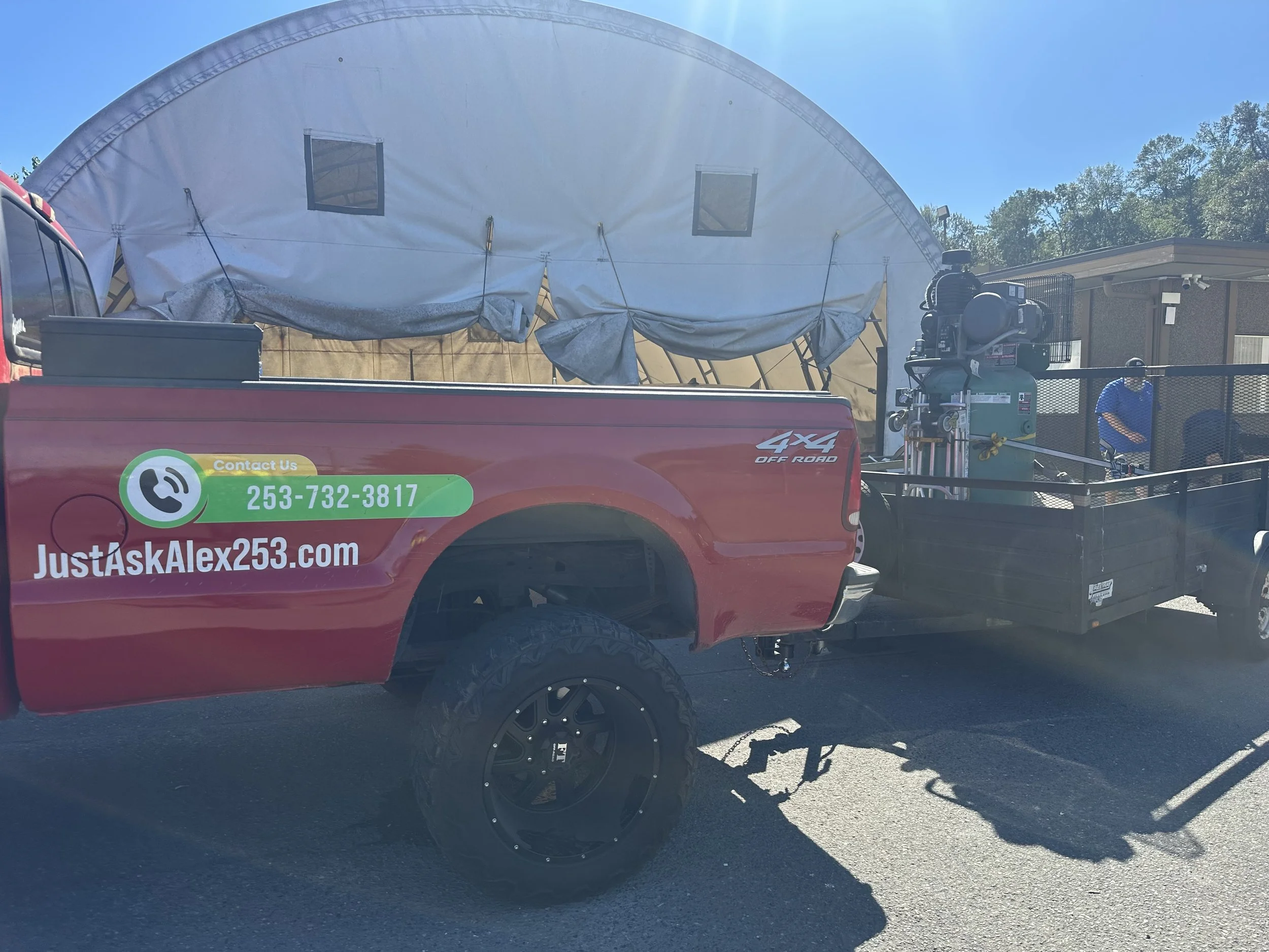 Large industrial air compressor secured on a utility trailer behind the Just Ask Alex work truck during commercial equipment removal in Tukwila.