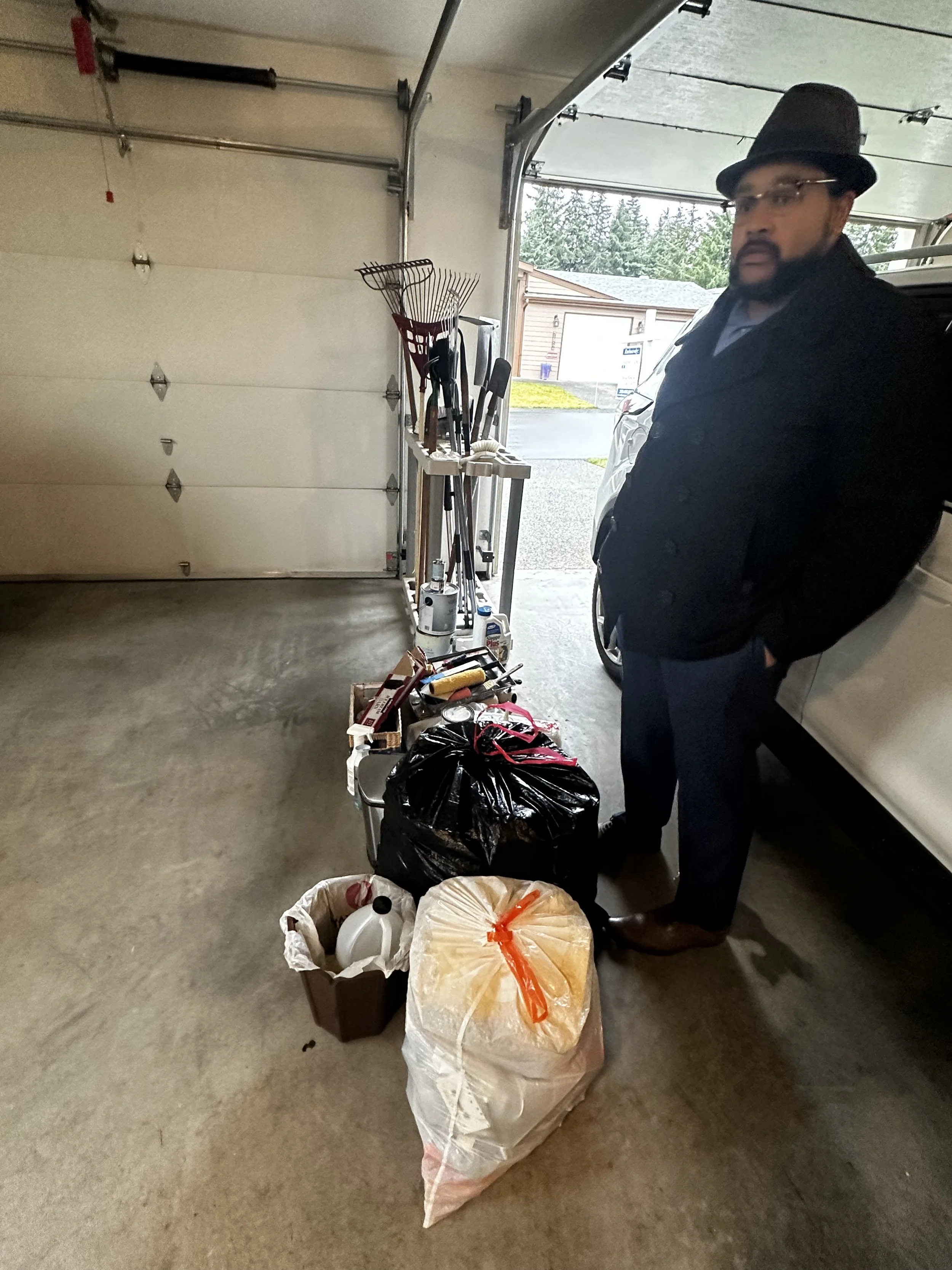 Before — Tools, garden rakes, and trash staged for pickup.