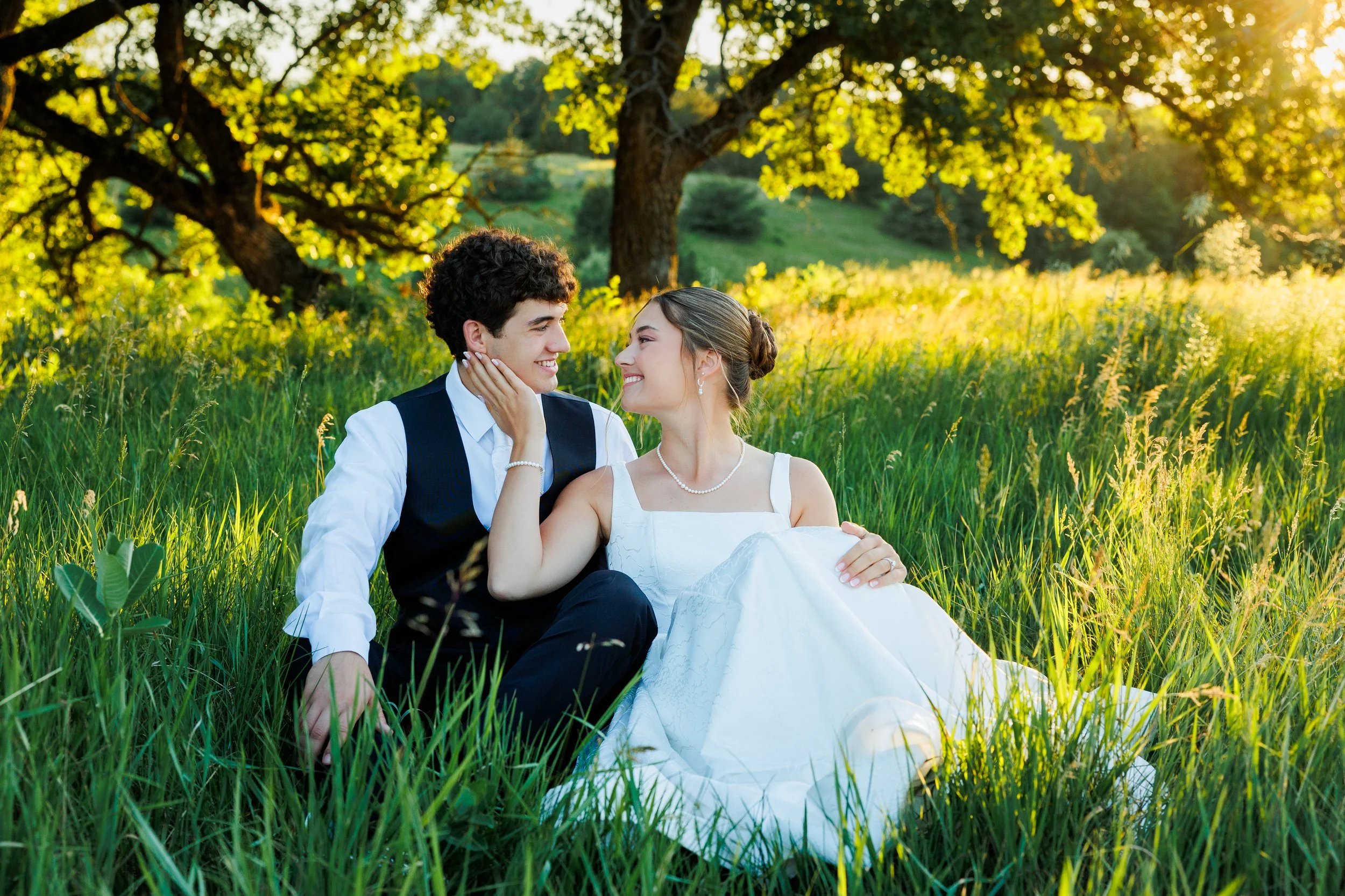 bride and groom sitting in tall grass