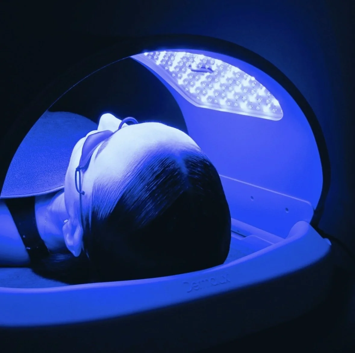 Person undergoing blue light therapy with a LED device