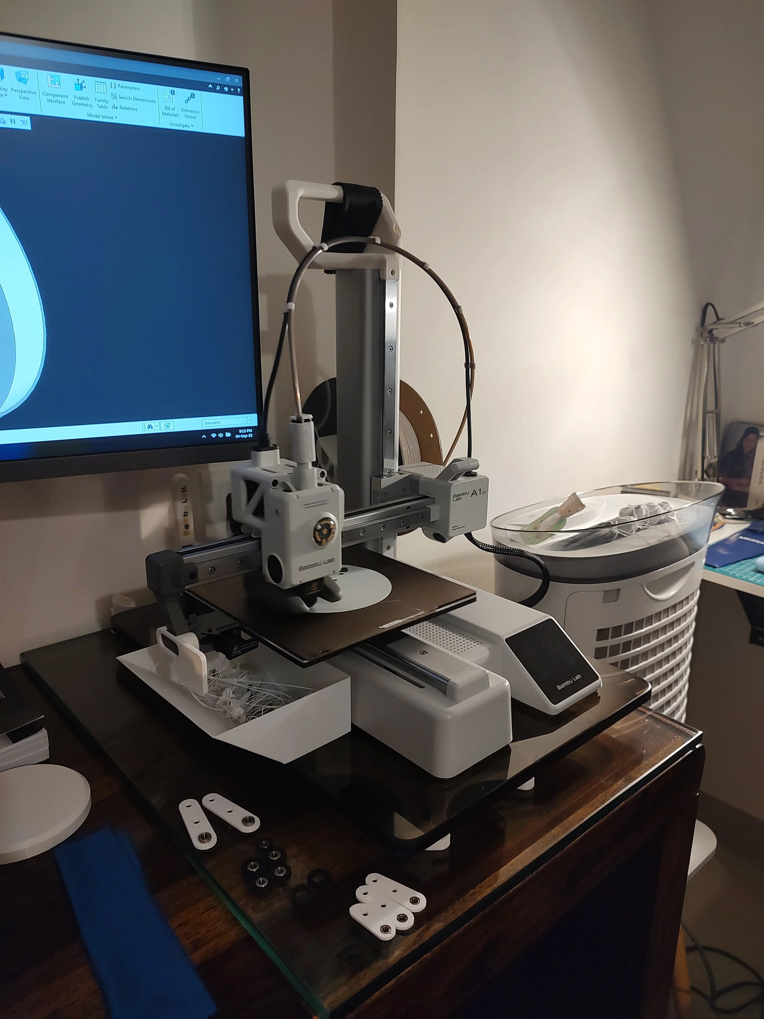 Laboratory 3D printer or scanner setup on a wooden desk with a monitor and various small parts.