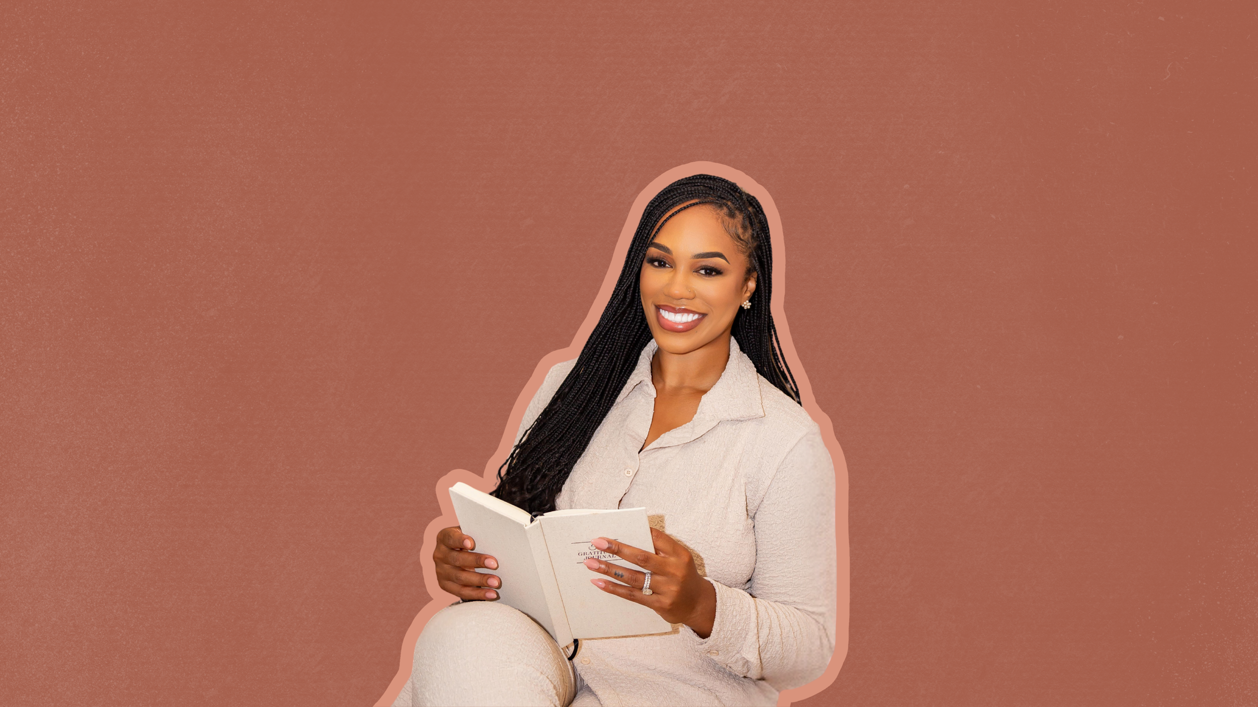 A woman with long braided hair, smiling, holding a white book, wearing a light-colored outfit, against a brown background.
