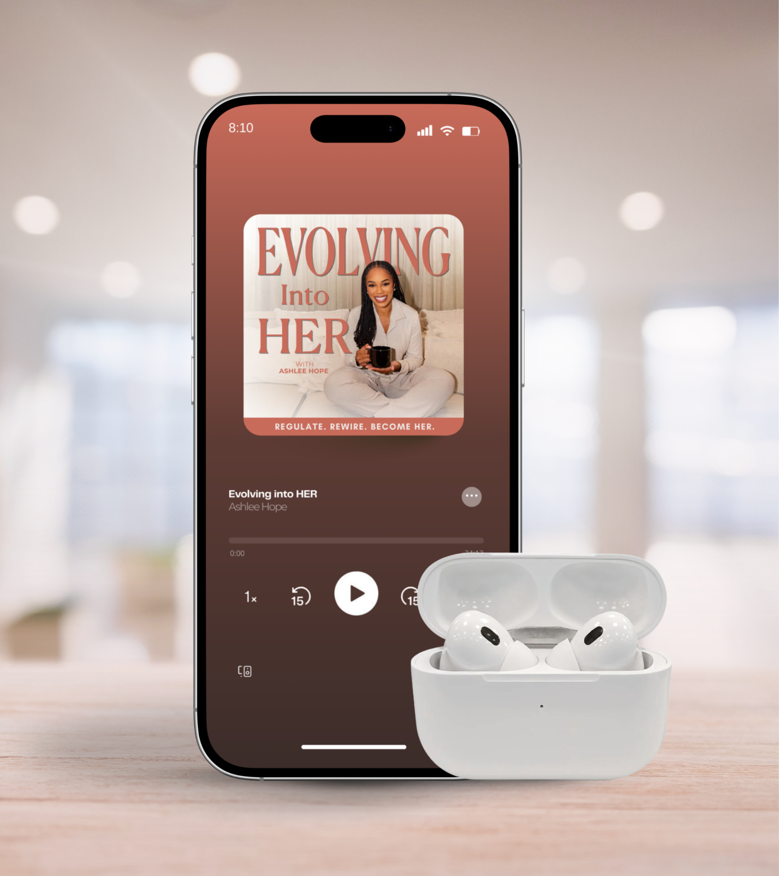 Smartphone playing an audiobook titled 'Evolving into HER' by Ashlee Hope, with wireless earbuds in front of it on a wooden surface.