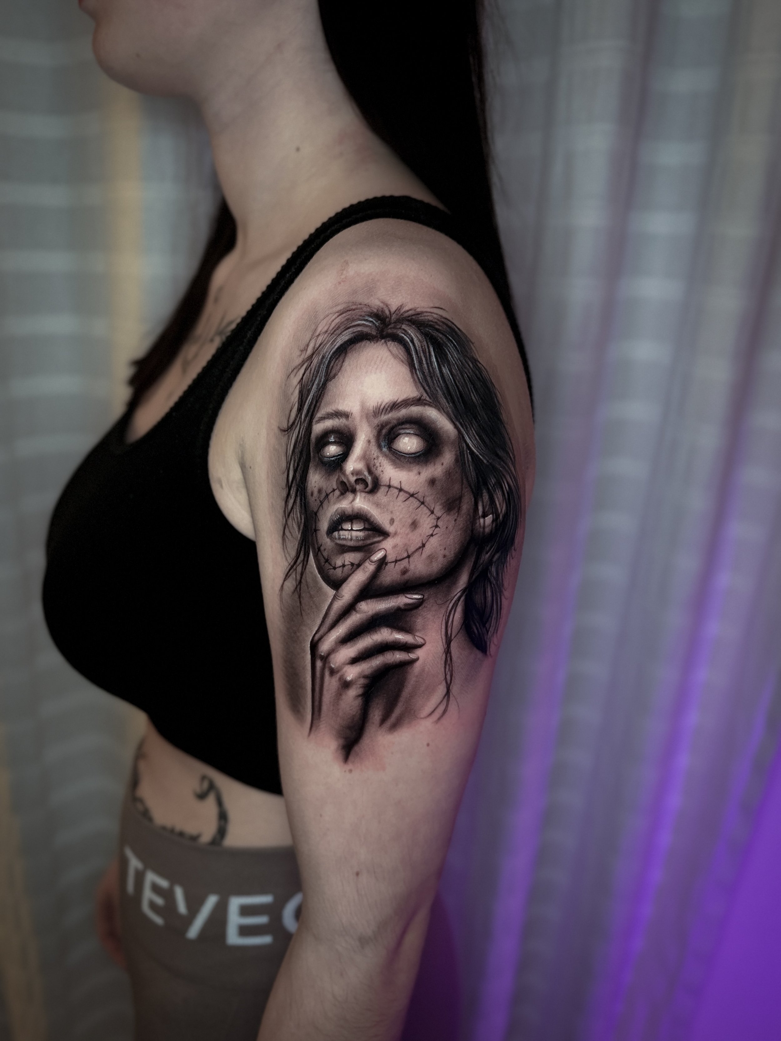 Black-and-Grey-Oberarmtattoo einer Zombiefrau mit weißen Augen und starkem Kontrast, gestochen im realistischen Dark-Style.