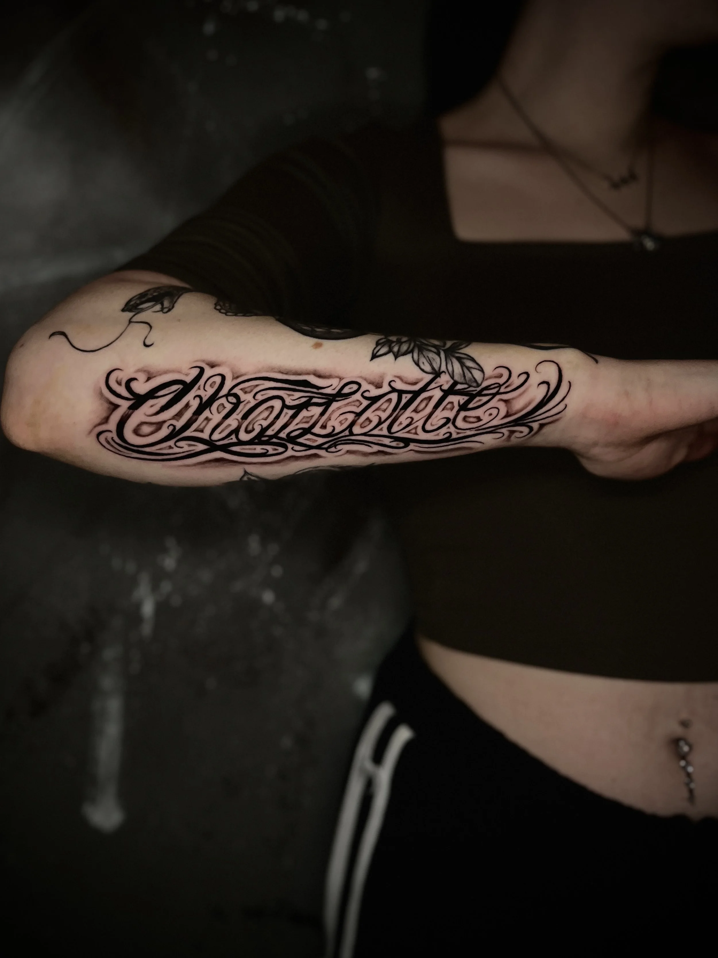 Fein ausgearbeitetes Lettering-Tattoo im kalligrafischen Stil mit dem Namen ‚Charlotte‘, gestochen auf dem Unterarm.