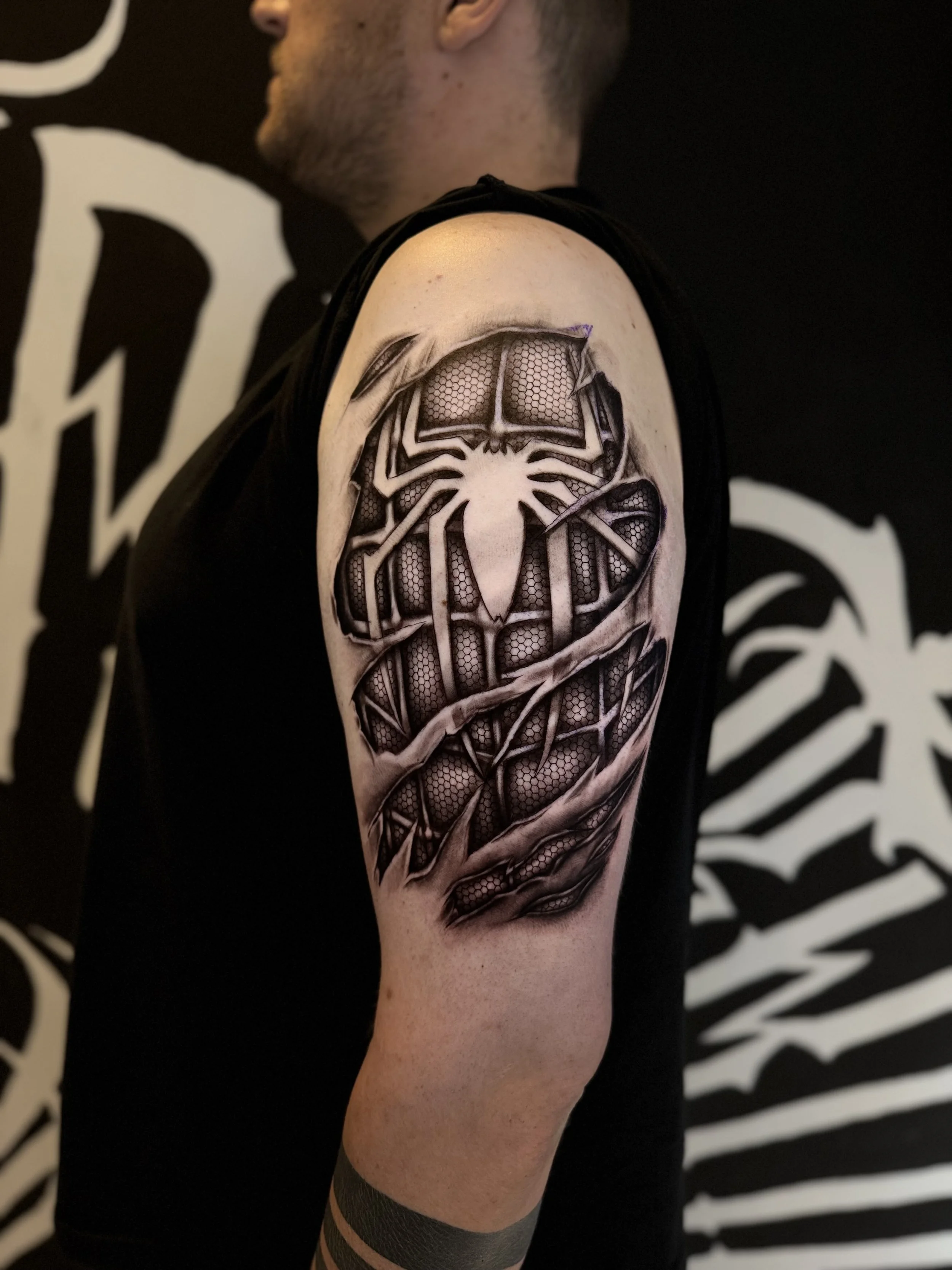 Spider-Man-Tattoo im Skin-Rip-Stil auf dem Oberarm, als würde die Haut aufgerissen sein.