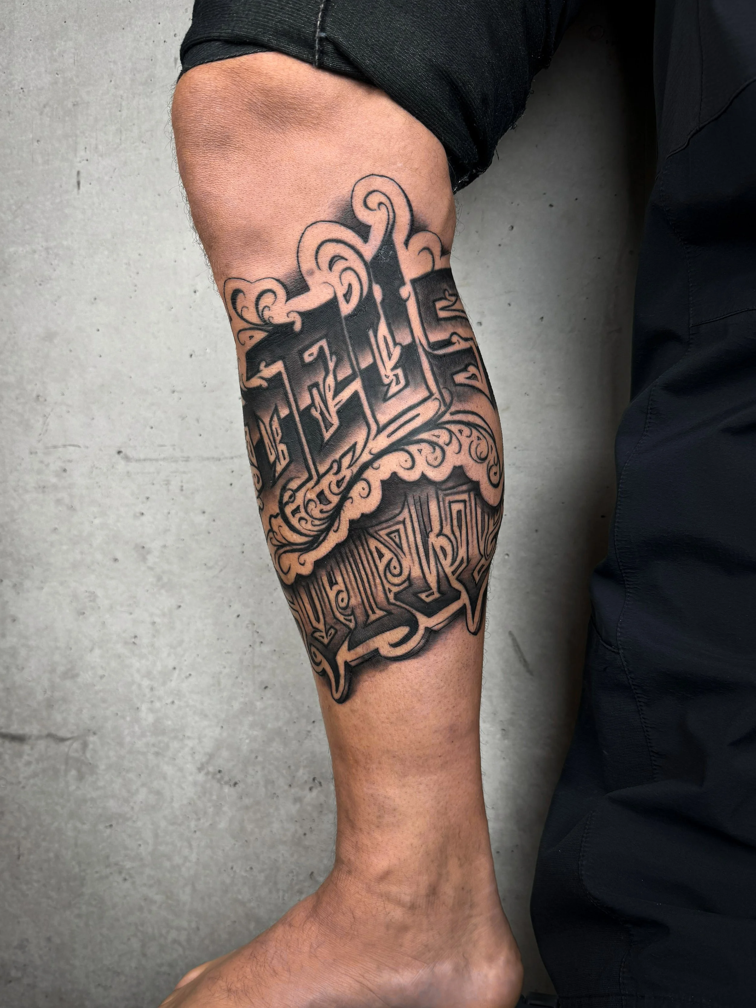 Freehand-Lettering-Tattoo mit dem Schriftzug ‚Deus vult‘ auf der äußeren Wade.