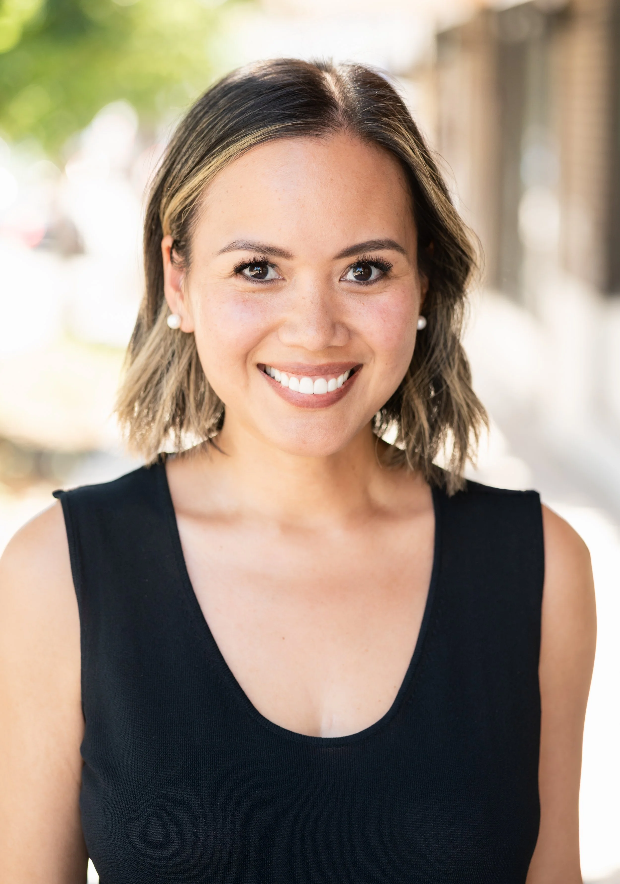 Profile photo of Founder & Principal, Nina Lai in black top against outdoor backdrop.