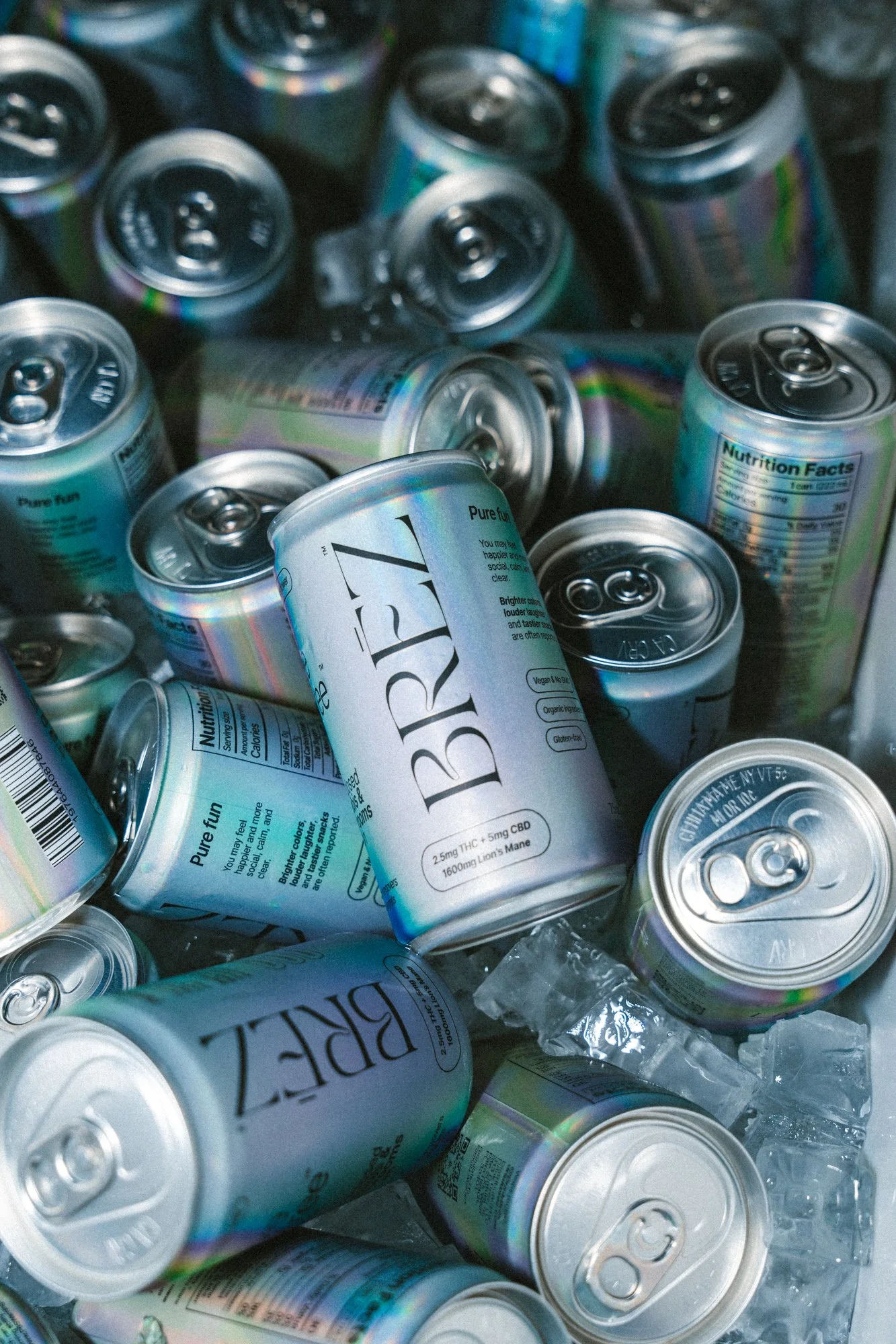 A pile of cans of beverage, with some ice cubes visible among them.
