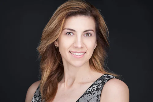 Headshot of a smiling woman with long auburn hair against a dark backdrop, ATX Headshots