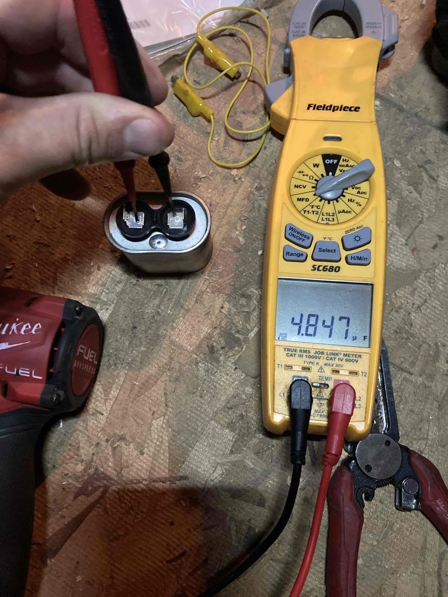 HVAC technician testing air conditioner capacitor with multimeter to diagnose AC running but not cooling