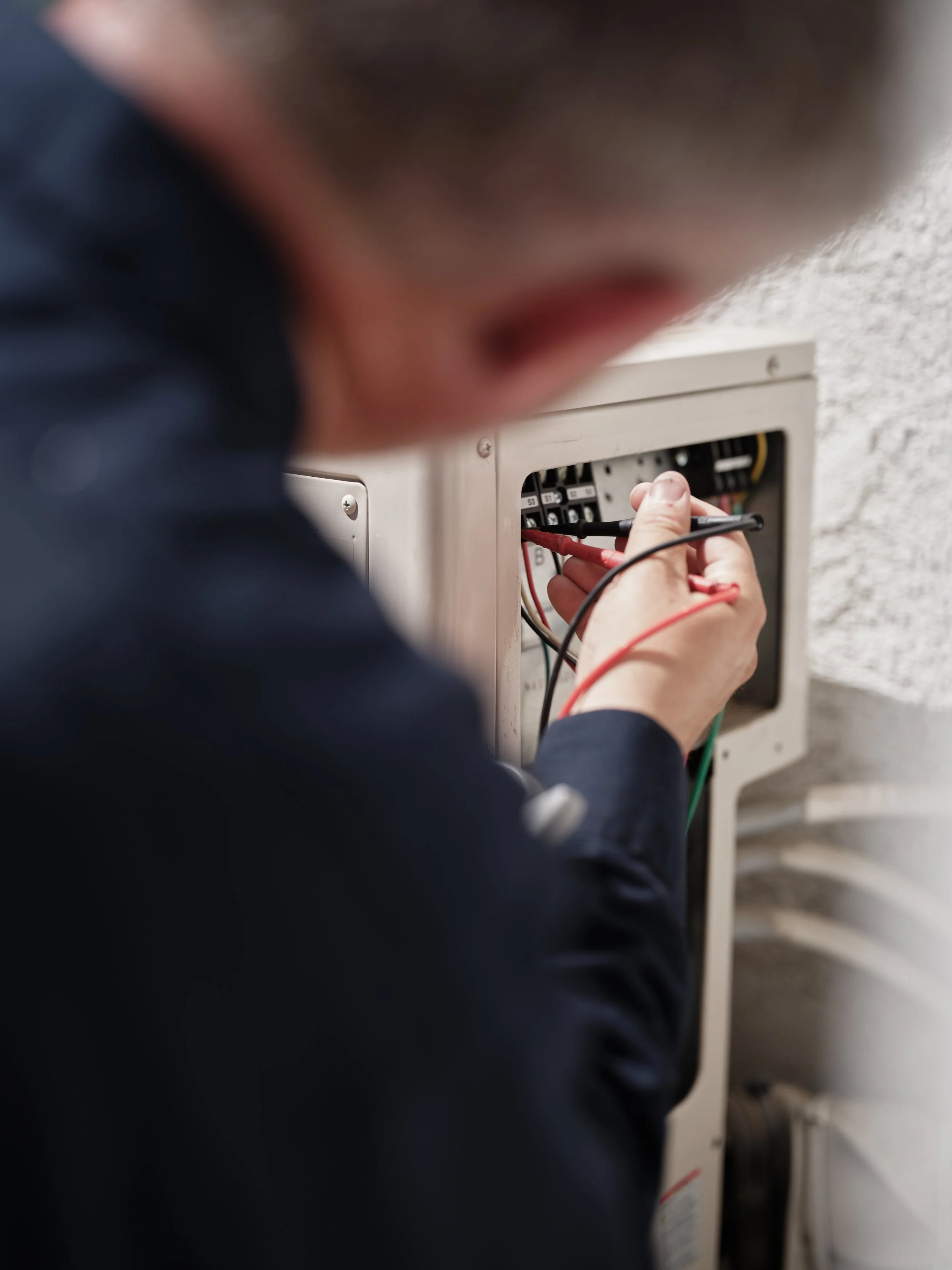 J Martin HVAC technician testing electrical connections during maintenance service in Anaheim