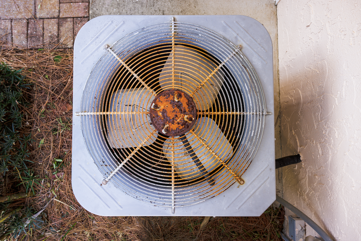 Overhead view of a severely rusted and corroded AC condenser fan and grille on an aging Orange County unit, one of the clearest visual warning signs that an air conditioning system has reached end of life and needs replacement rather than repair