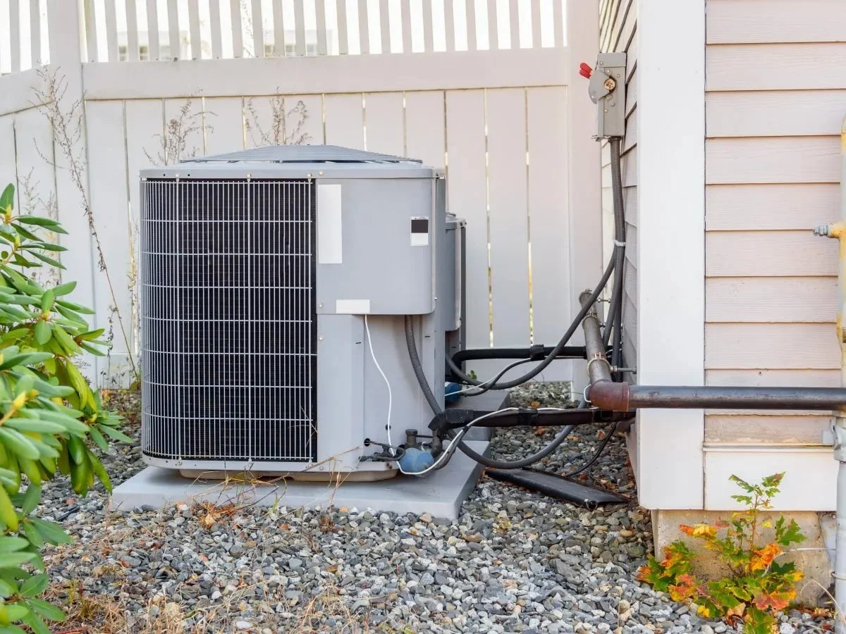Outdoor AC unit with condensate drain line where clogged AC drain can exit home