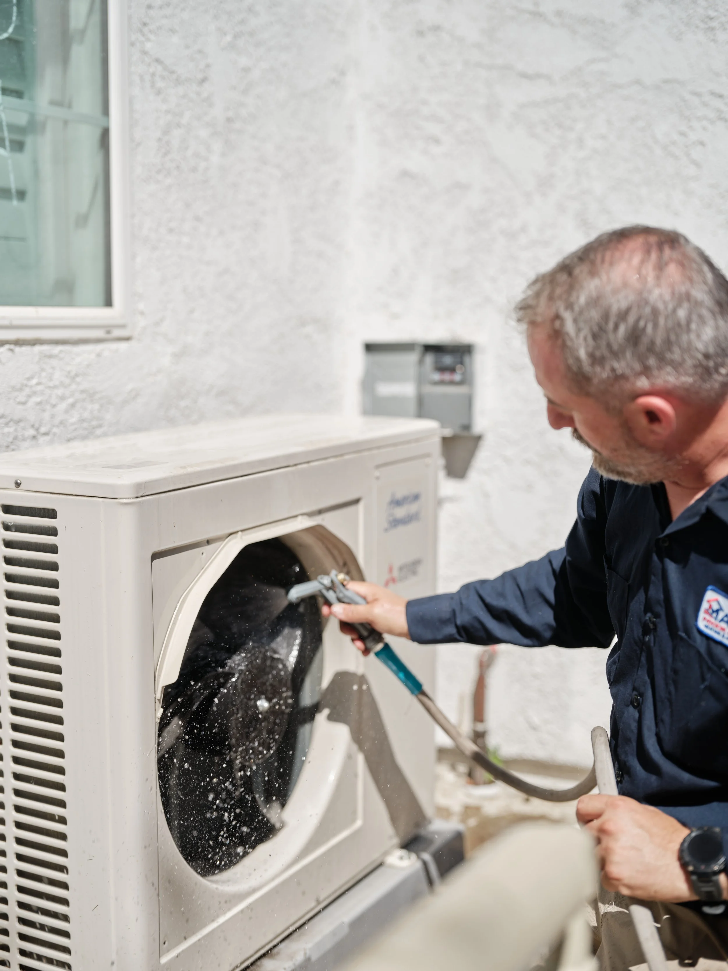 HVAC technician cleaning dirty condenser coil covered with debris to fix AC short cycling problem
