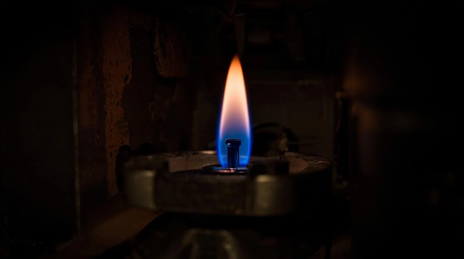 healthy blue pilot light flame in gas furnace burner assembly indicating proper combustion
