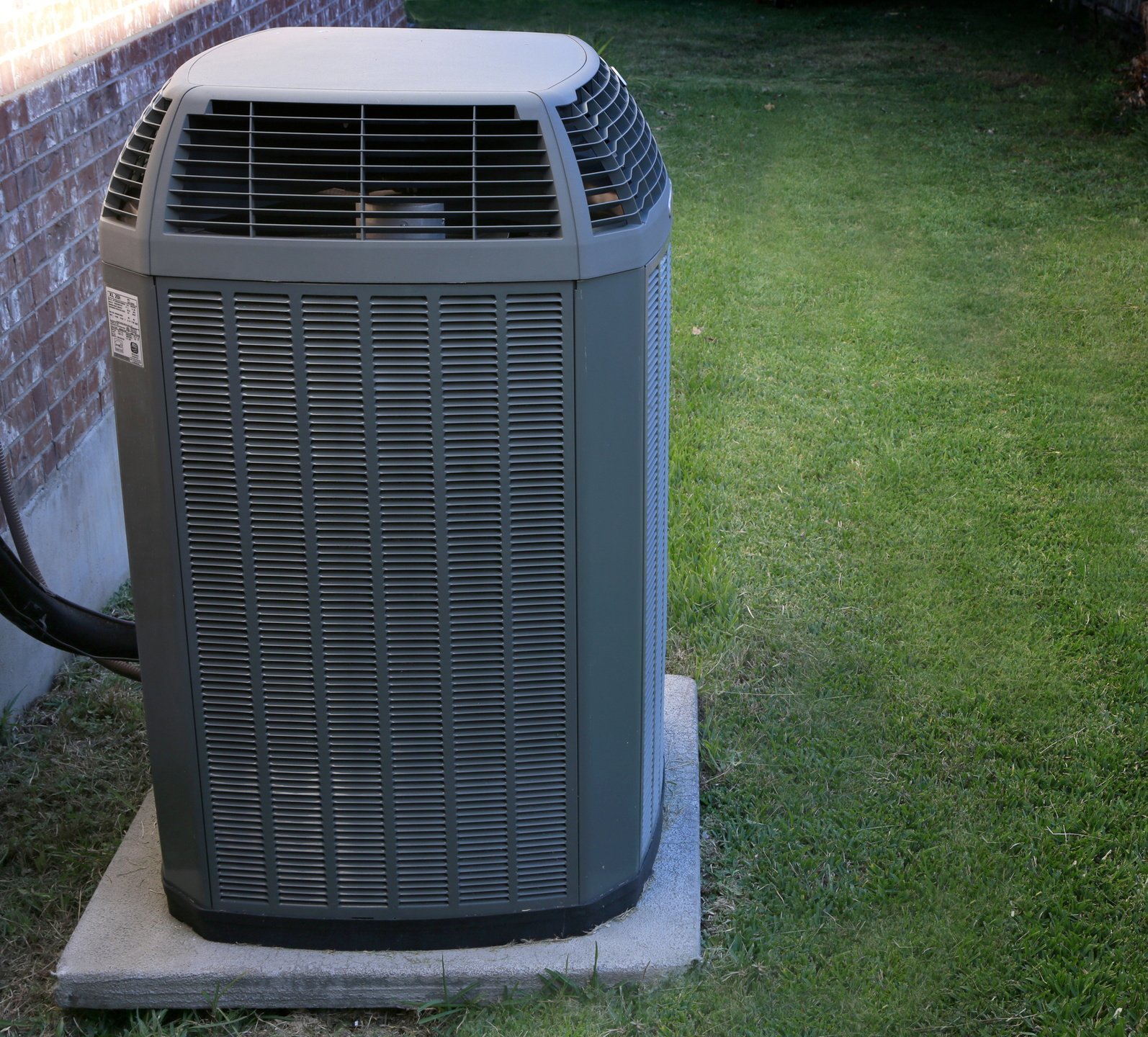 Outdoor residential air conditioner condenser unit installed beside a home
