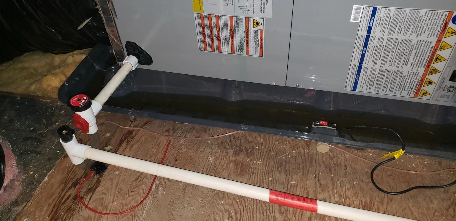 Attic HVAC air handler with PVC condensate drain line and cleanout