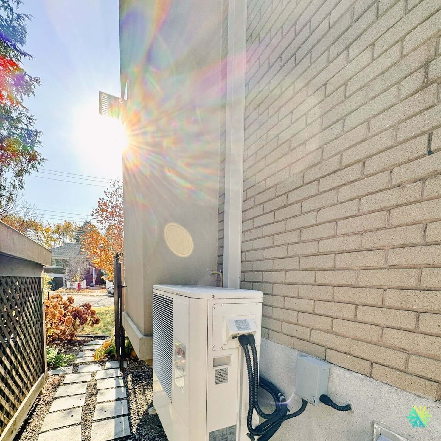 Heat pump outdoor condenser unit installed beside brick home exterior