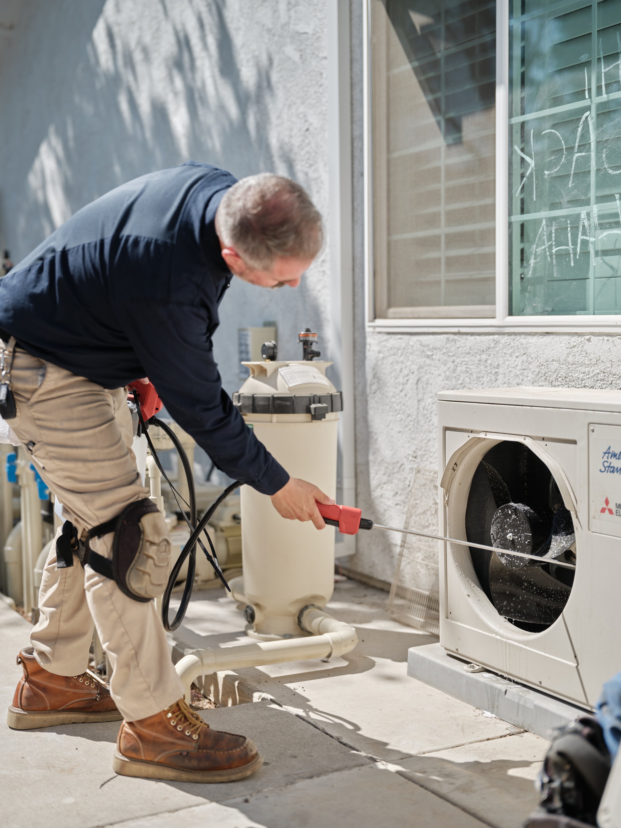 Certified HVAC technician servicing Mitsubishi ductless mini-split outdoor unit at Yorba Linda residence