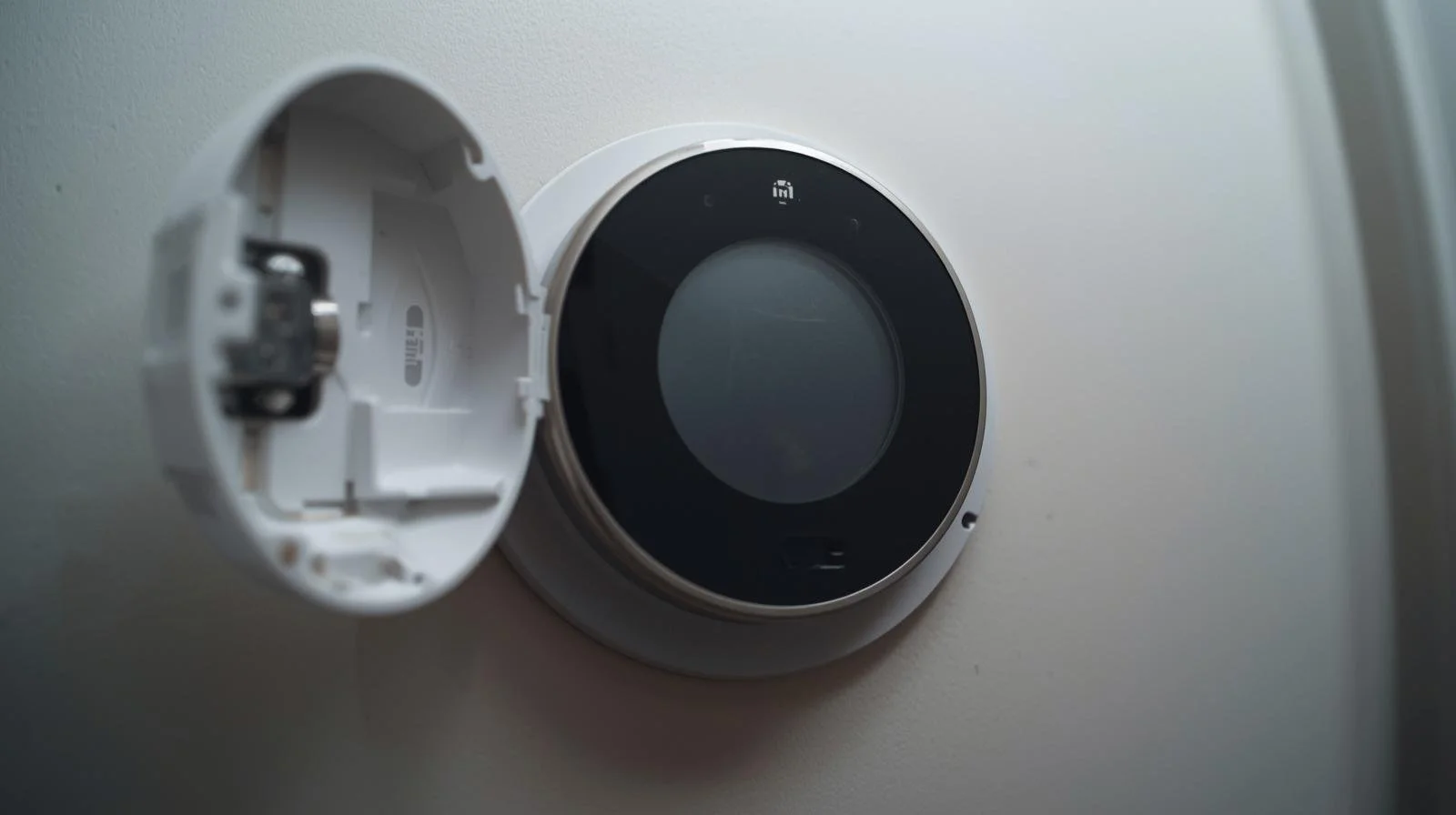 Smart thermostat with battery compartment open showing batteries that need replacement before holiday season