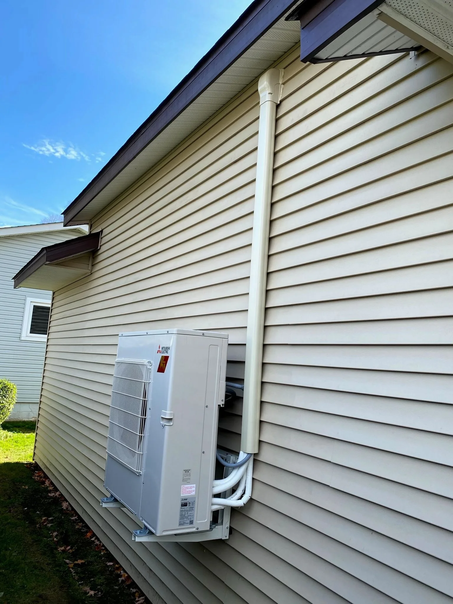 Mitsubishi Electric multi-zone mini split condenser wall-mounted on exterior of home with line set cover