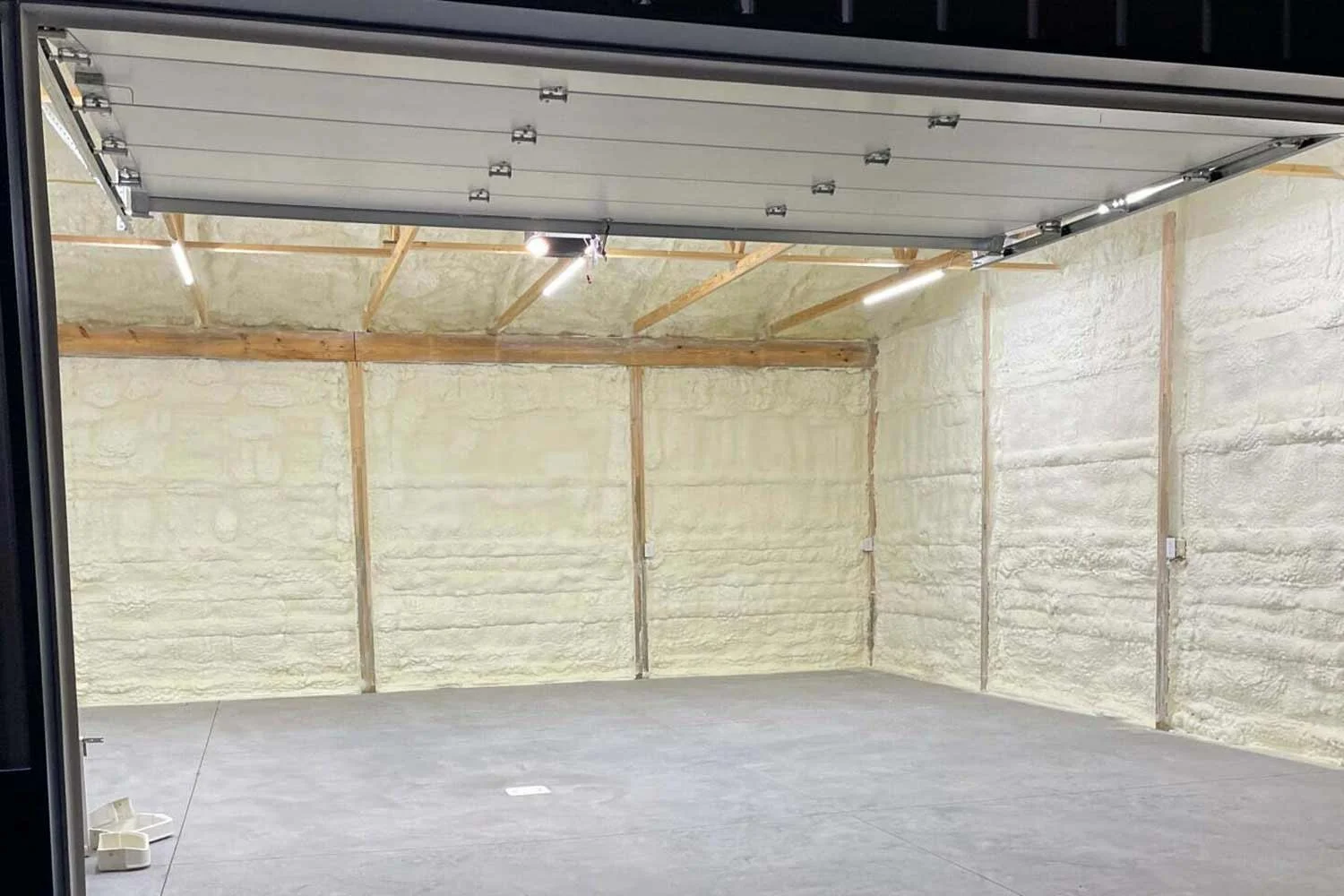 Spray foam insulation applied to walls and ceiling rafters of a garage conversion before drywall