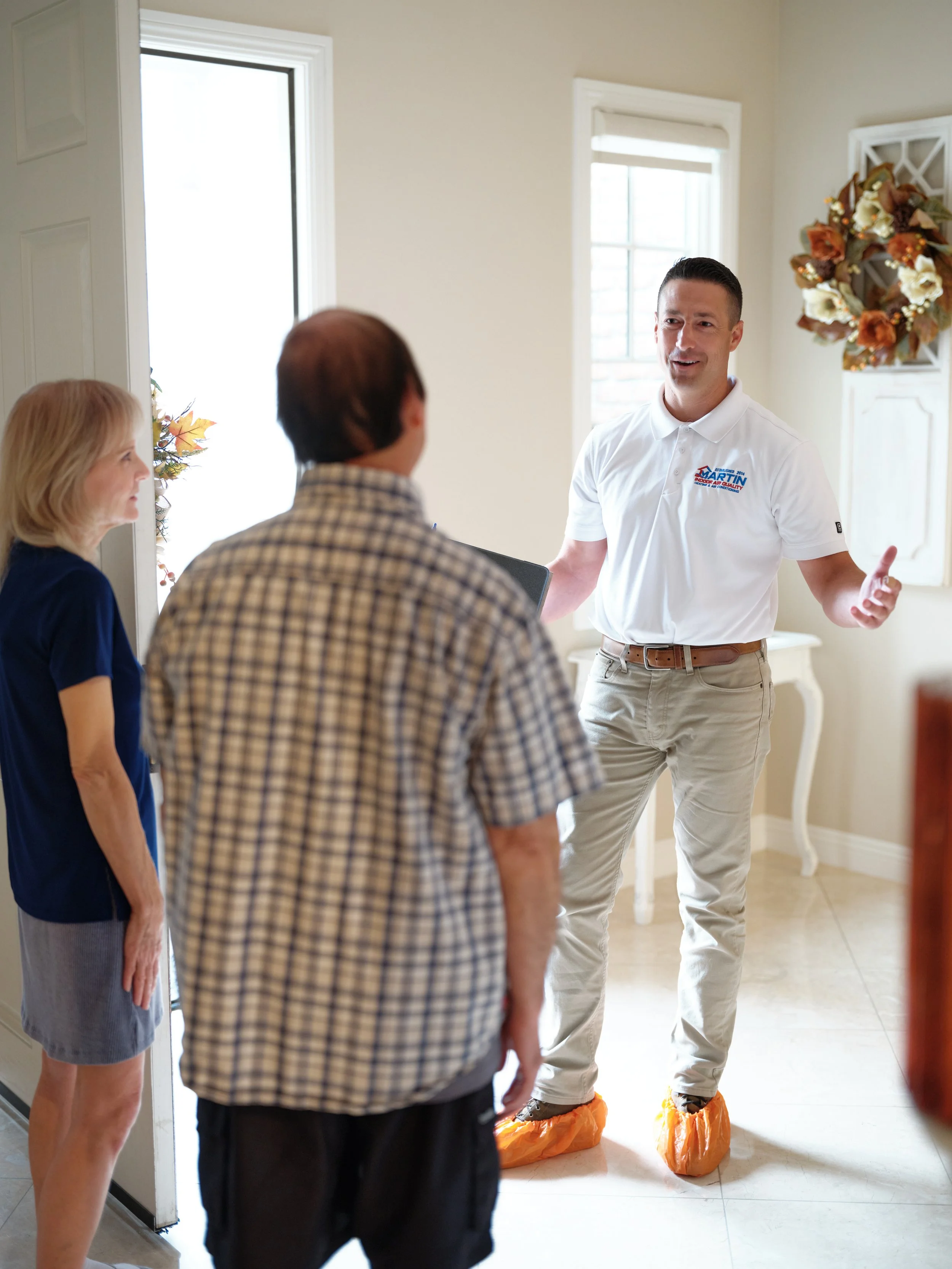 Licensed HVAC technician explaining California HVAC rebates and tax credits to Orange County homeowners during home consultation