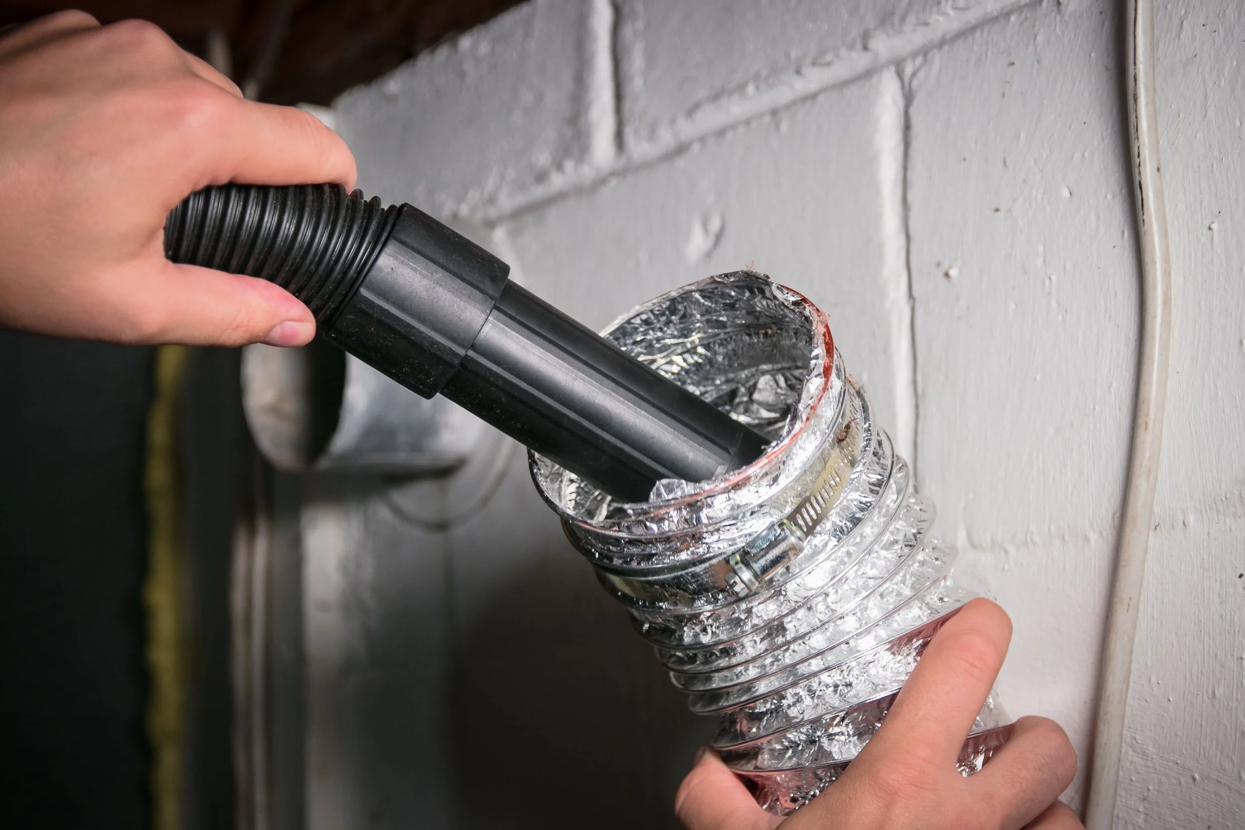 Vacuum removing dust and debris from HVAC air duct during professional duct cleaning service