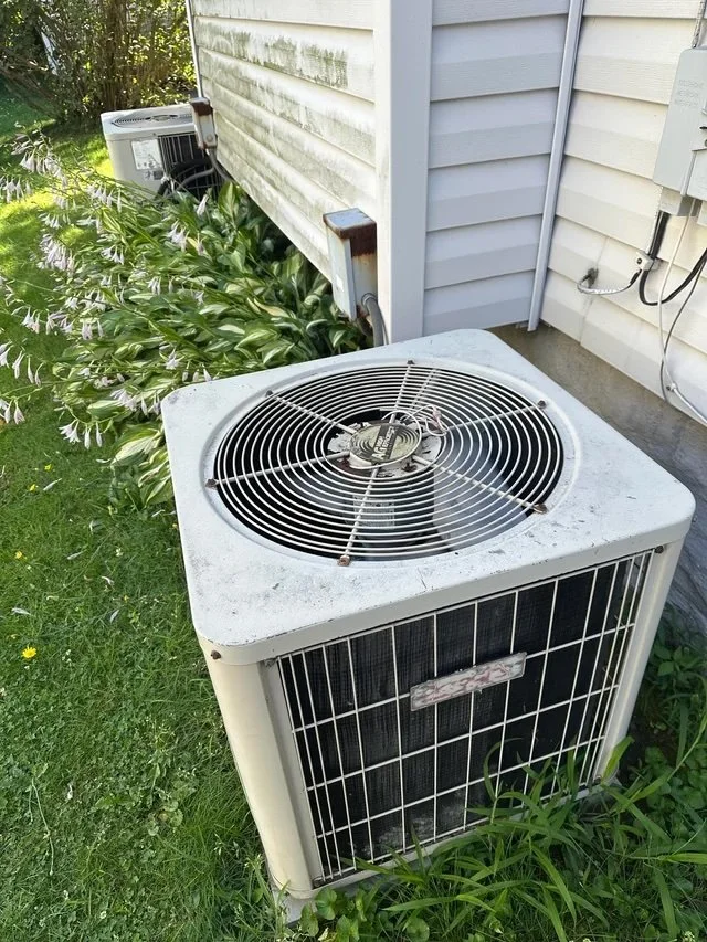 aging outdoor AC condenser unit with rust and faded paint showing signs of end-of-life wear