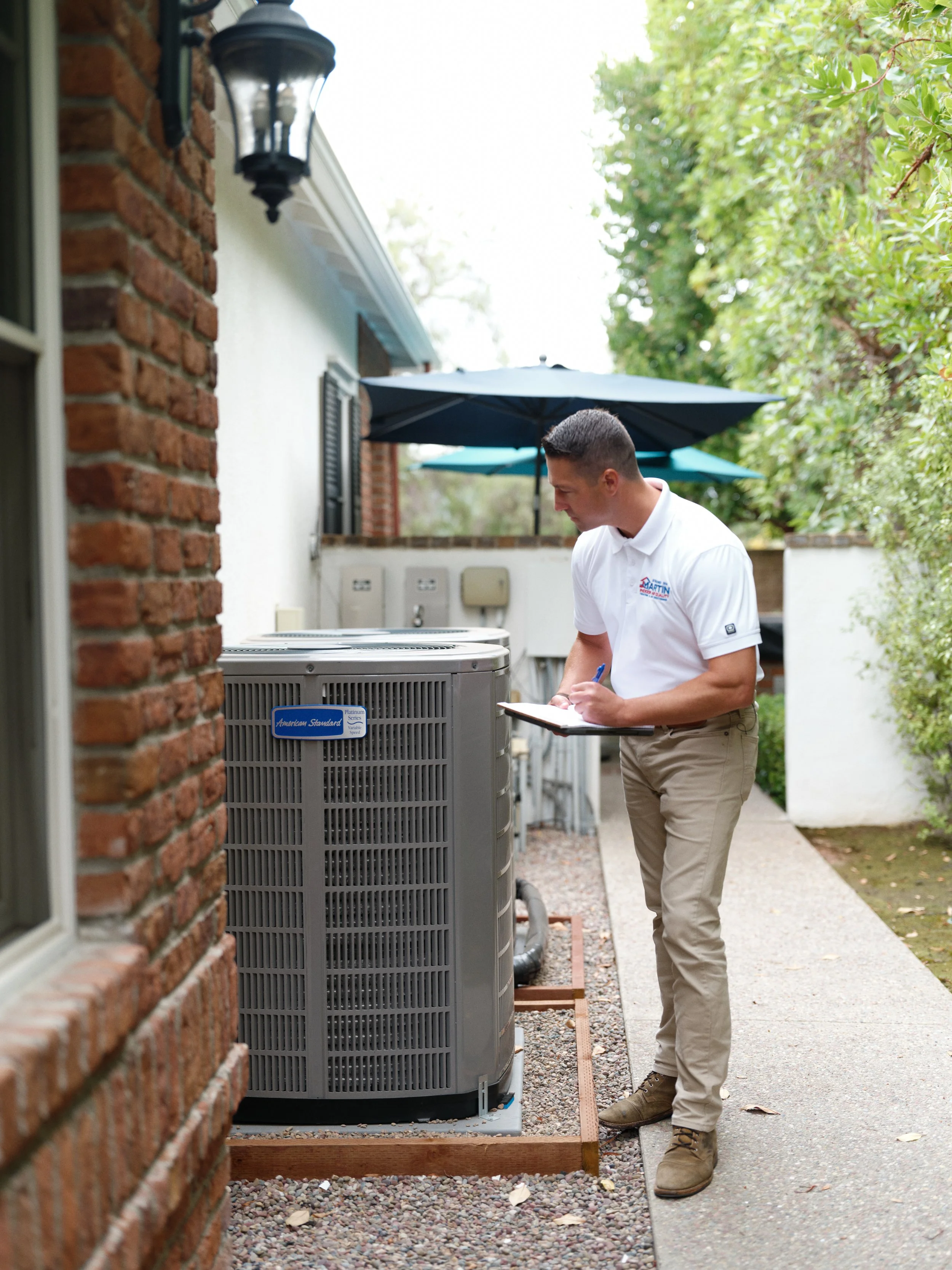 HVAC technician inspecting outdoor air conditioning unit during AC tune-up in Orange County
