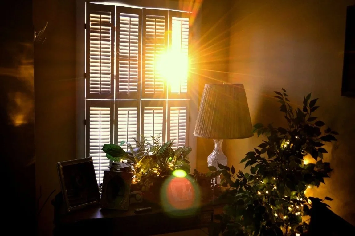 Sunlight streaming through window blinds heating a room, causing temperatures to feel warmer than the thermostat reading