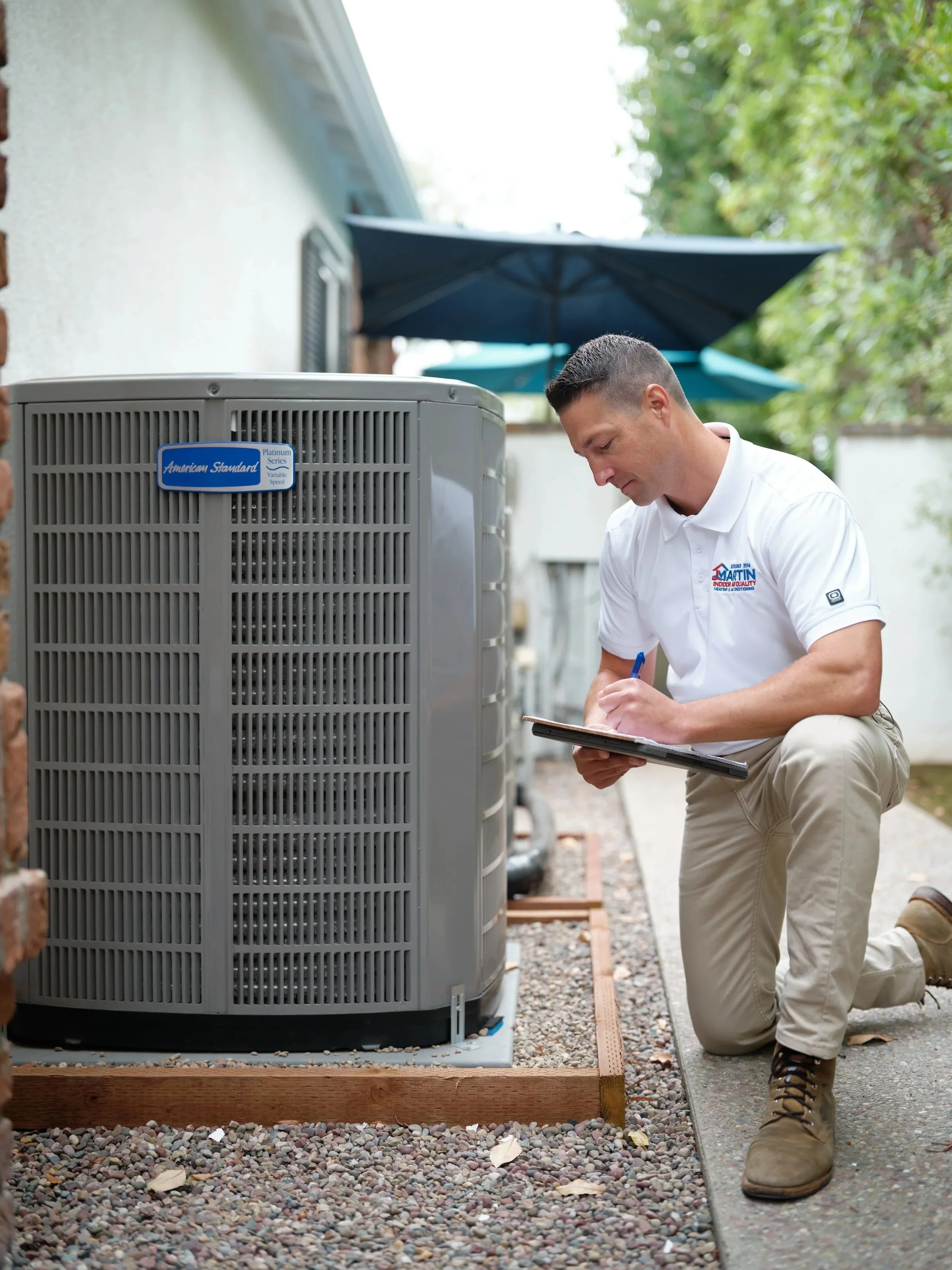 J Martin HVAC technician inspecting an American Standard AC condenser unit in Orange County