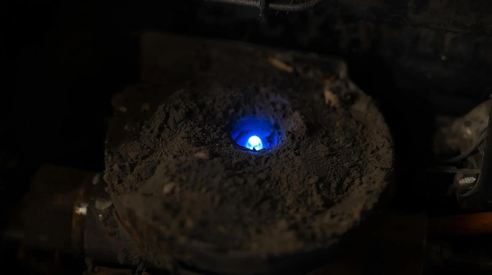 black soot buildup around gas furnace burner indicating incomplete combustion and safety concern