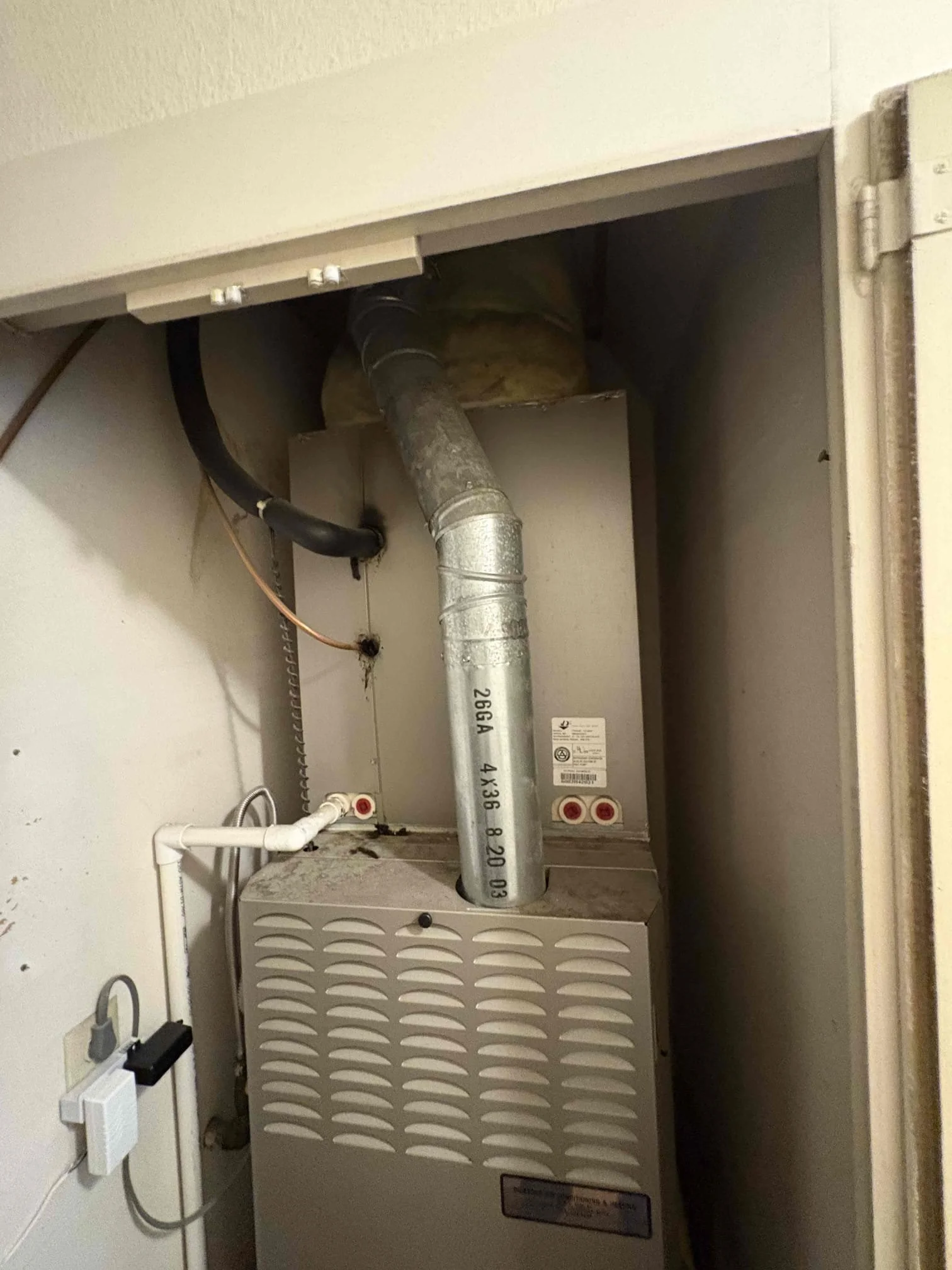 Gas furnace not working in Orange County home showing aging unit with metal flue pipe and access panel in closet installation