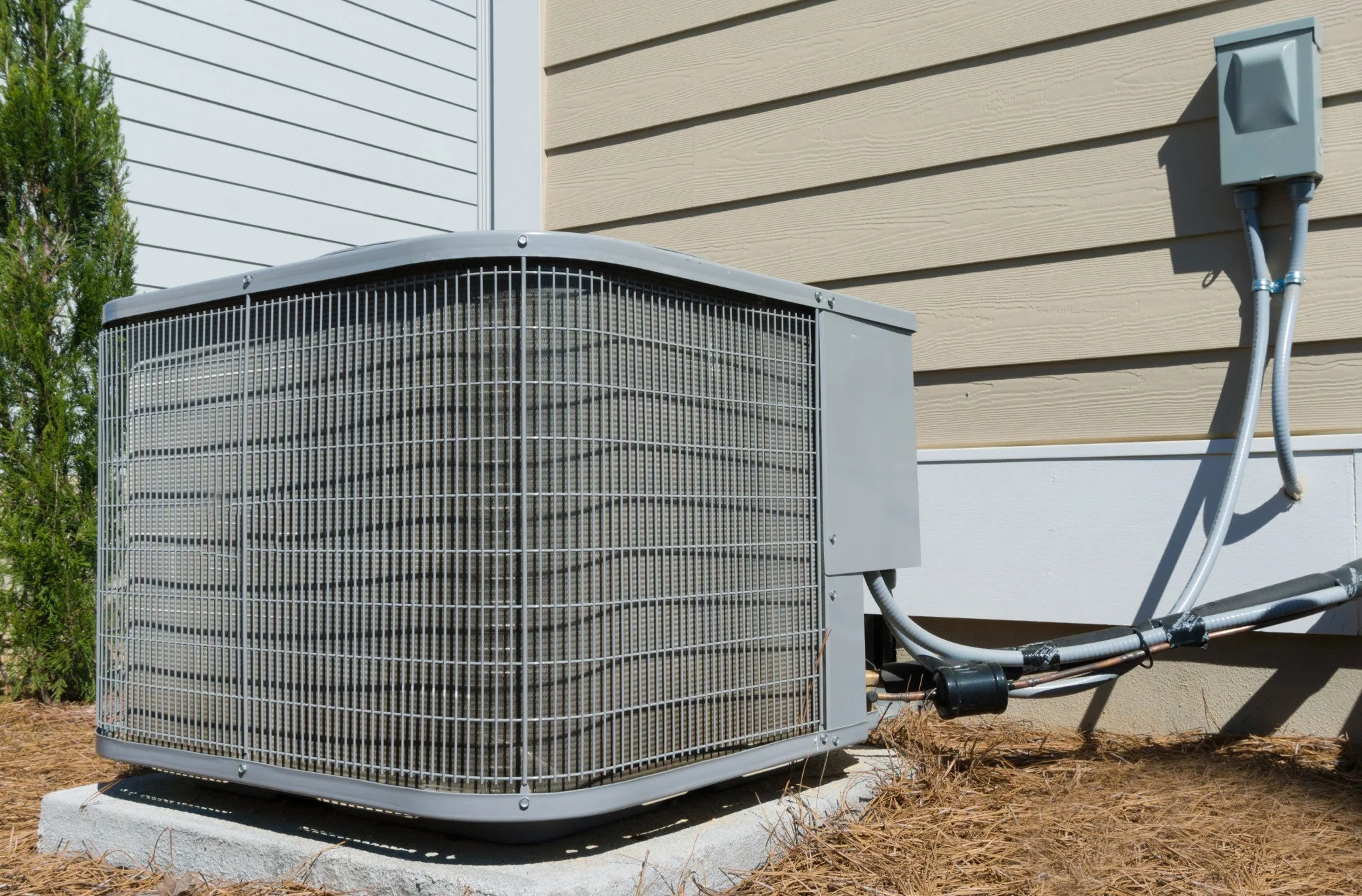 Residential outdoor air conditioner condenser unit installed beside a house