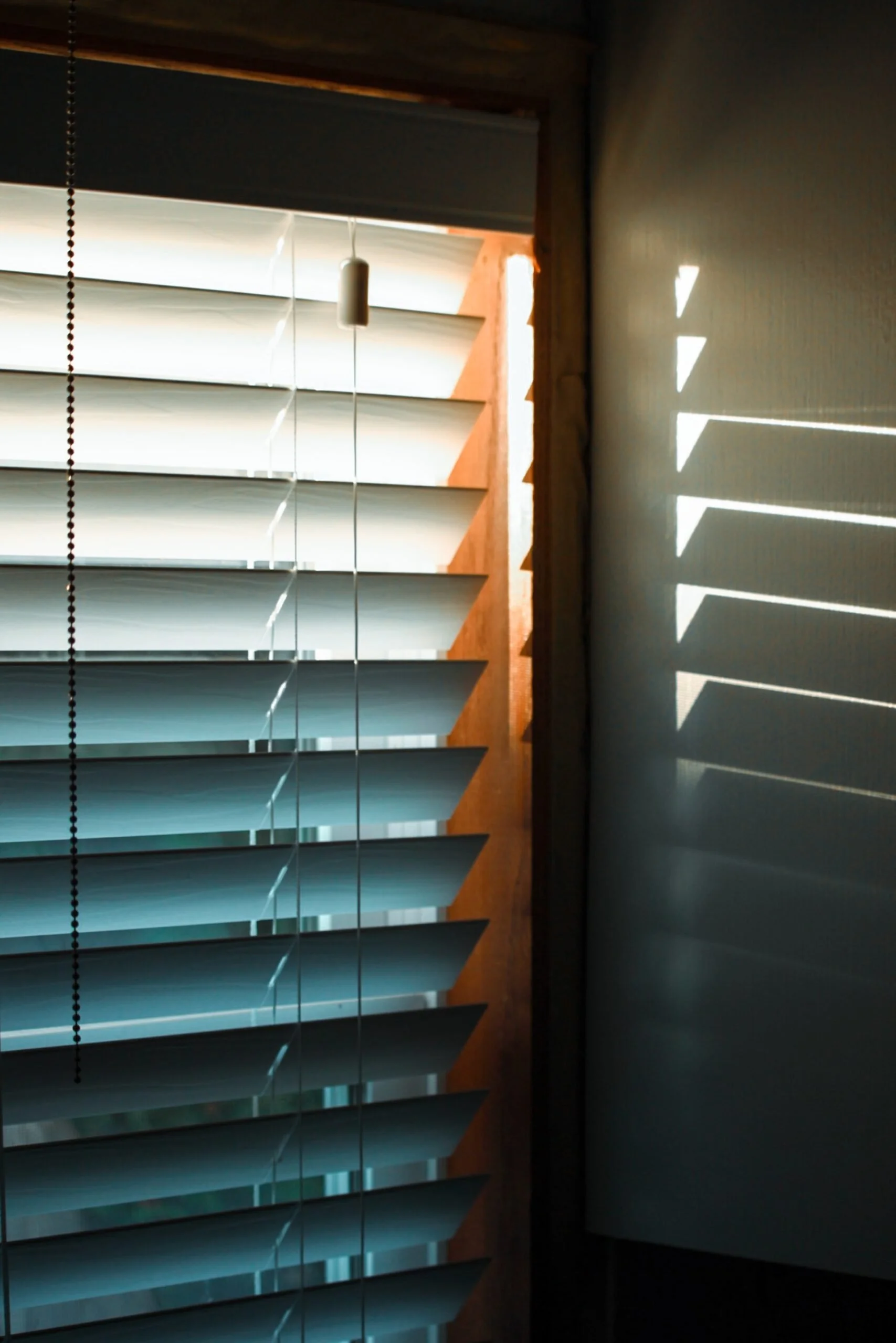 Sunlight shining through window blinds inside a home, illustrating how sunlight can heat indoor spaces.