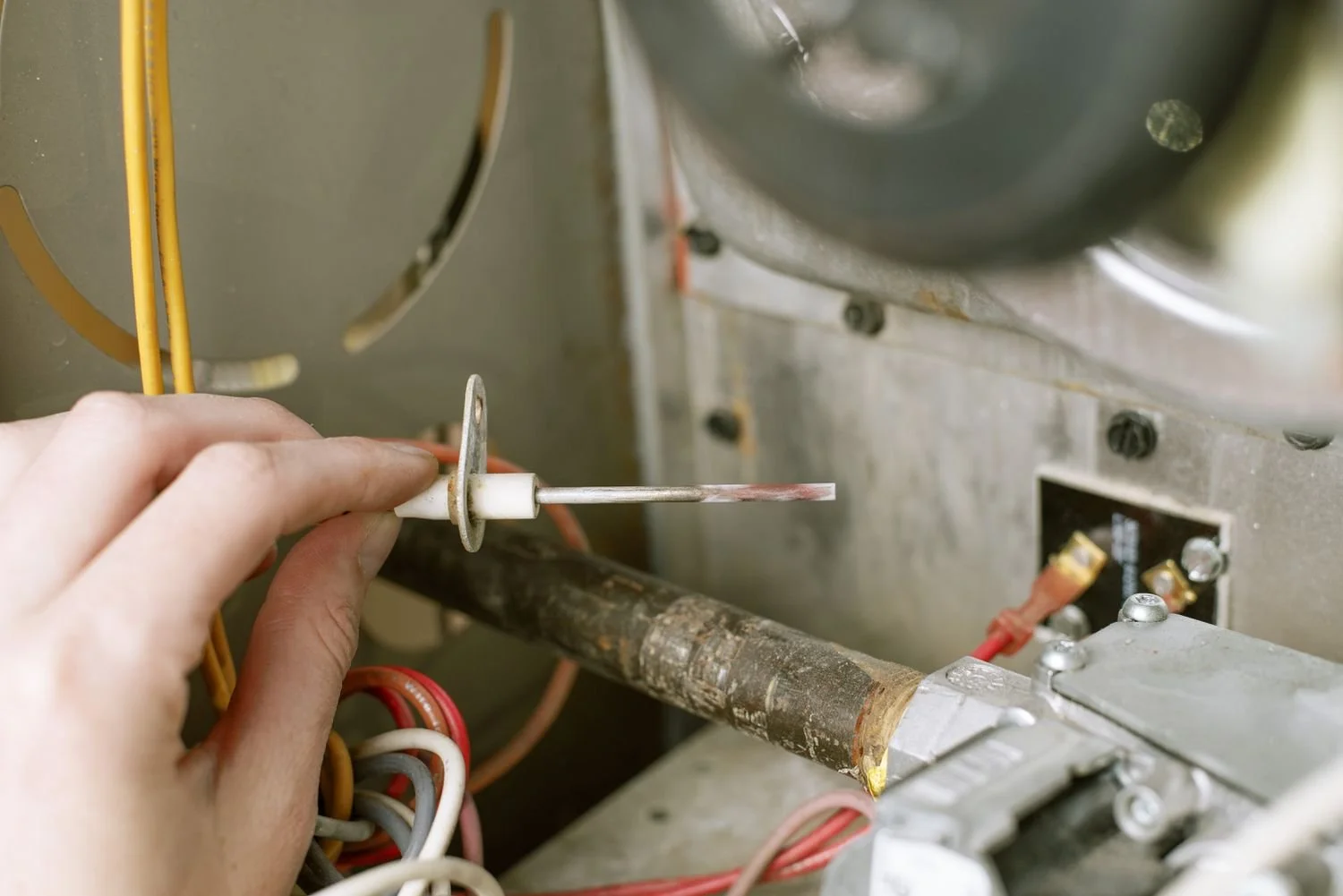 HVAC technician removing a flame sensor from a furnace burner assembly in Orange County