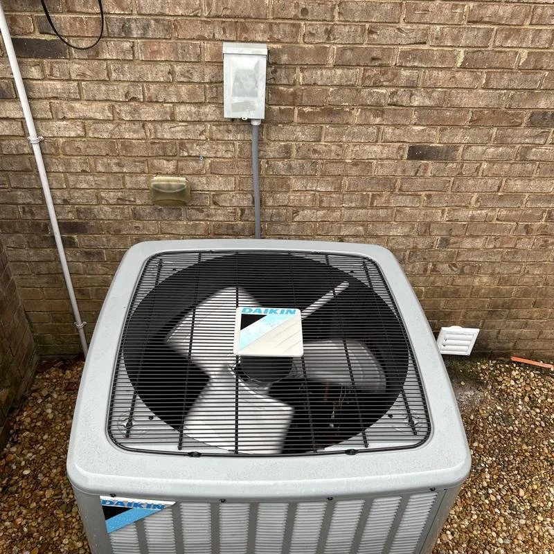 Daikin outdoor air conditioner unit installed beside brick home for residential HVAC cooling system