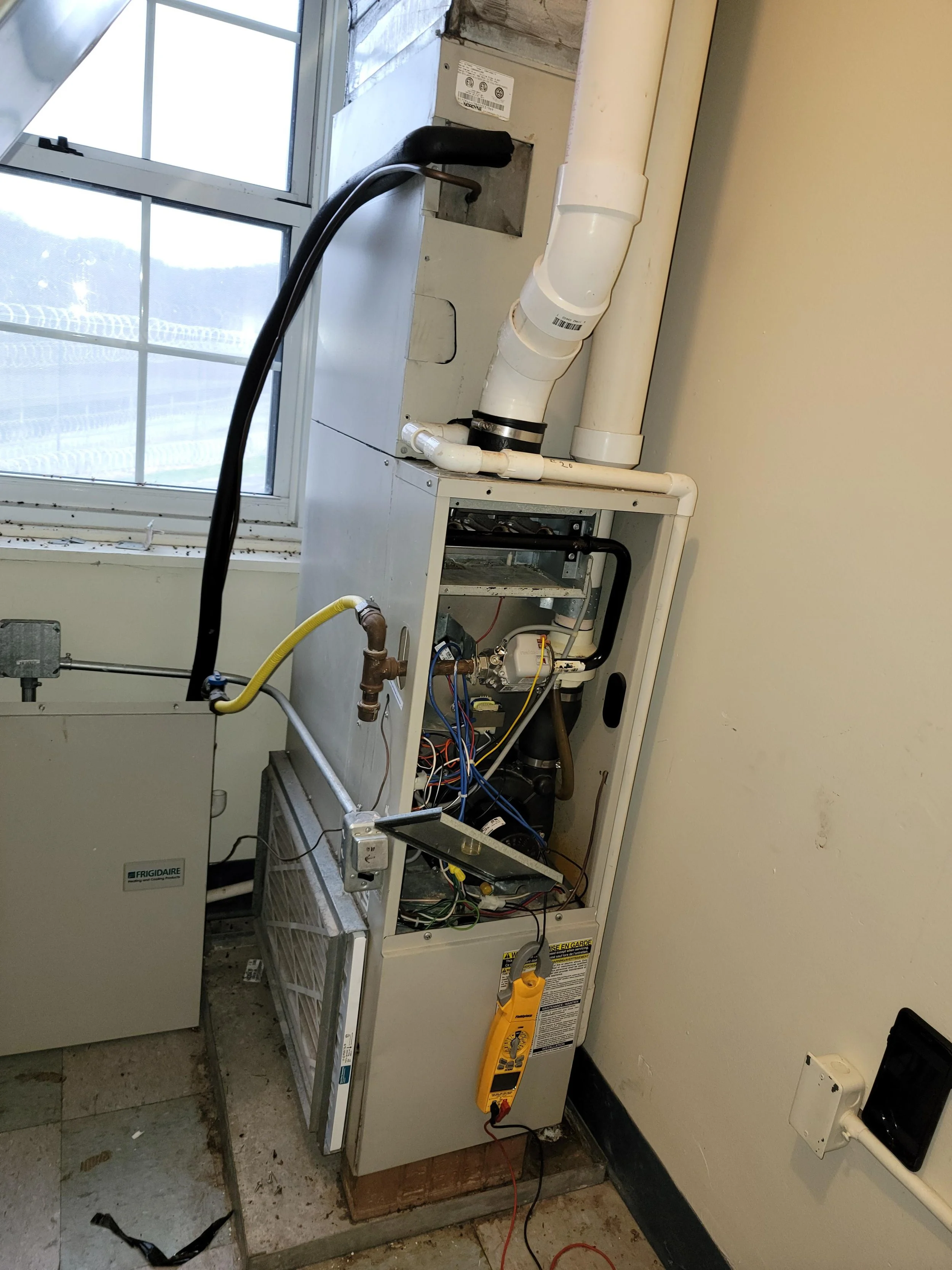 HVAC technician inspecting furnace heat exchanger and internal components during maintenance service
