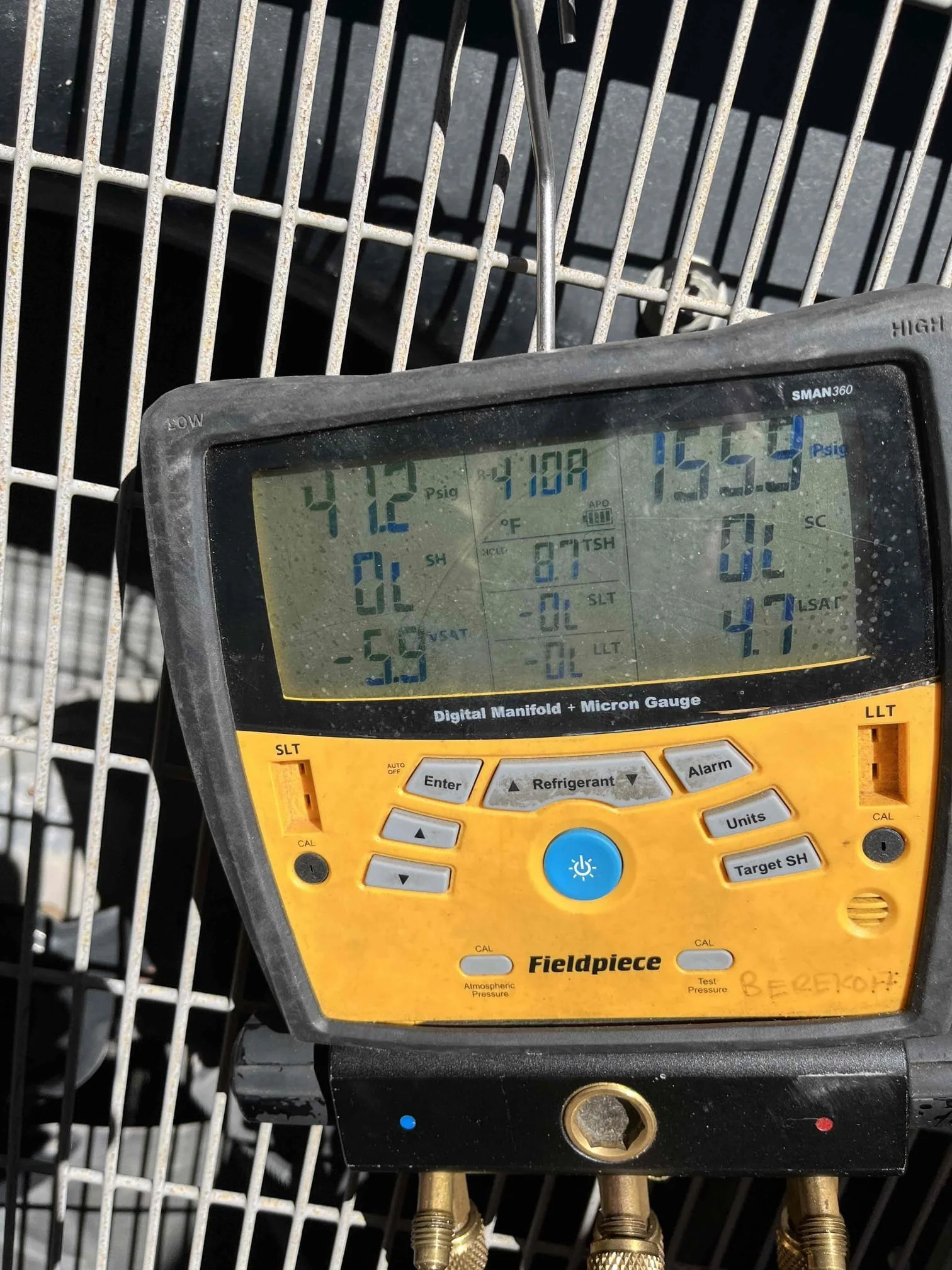 Fieldpiece digital manifold gauge displaying R-410A refrigerant pressure readings on an outdoor AC unit during a Santa Ana wind season service call in Orange County