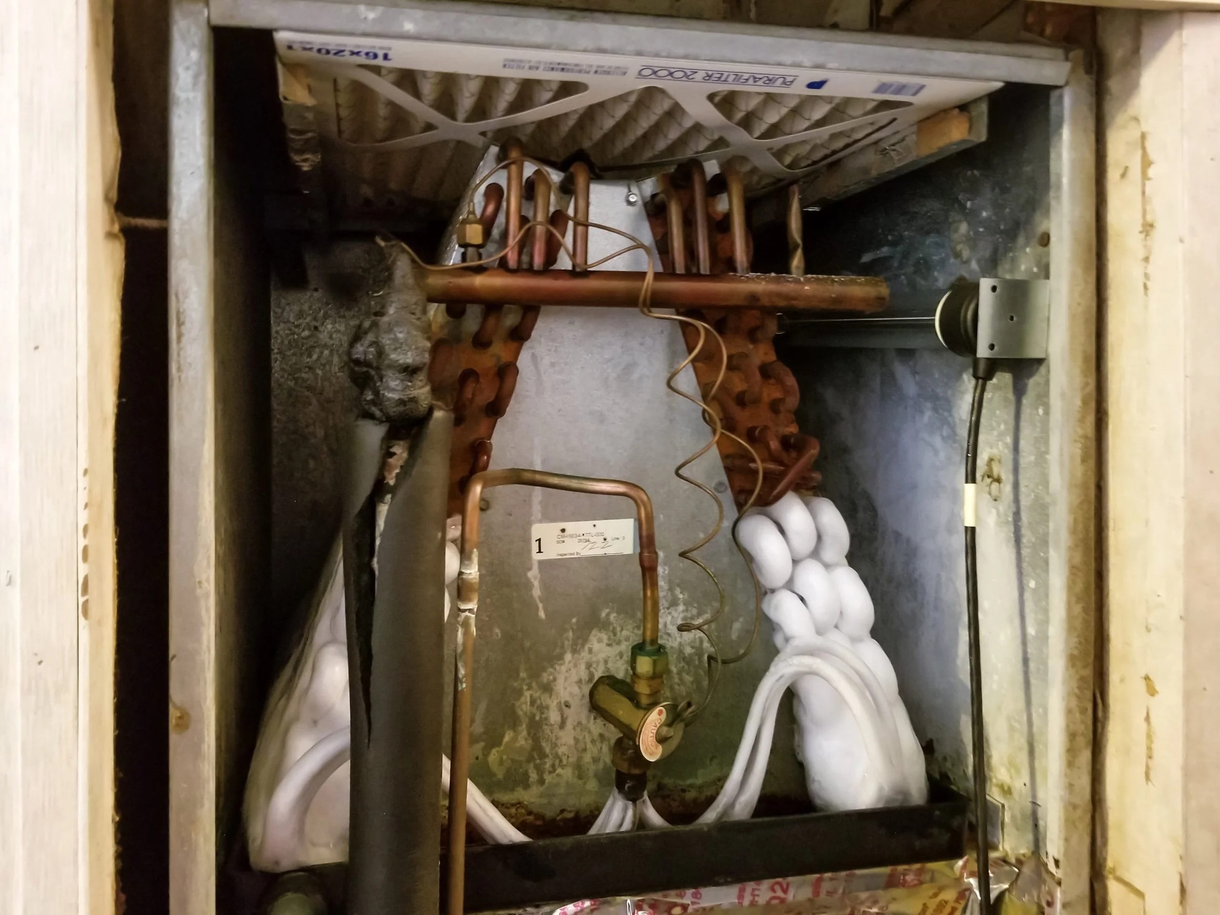 frozen evaporator coil with heavy ice buildup on refrigerant lines and valve inside an Orange County air handler
