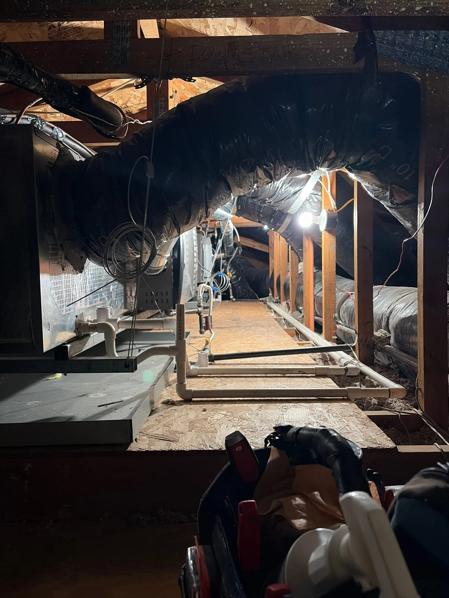 J Martin Indoor Air Quality technician inspecting attic HVAC ductwork and air handler in a Yorba Linda home, showing deteriorated duct insulation and condensate drain lines that a standard home inspection would not evaluate