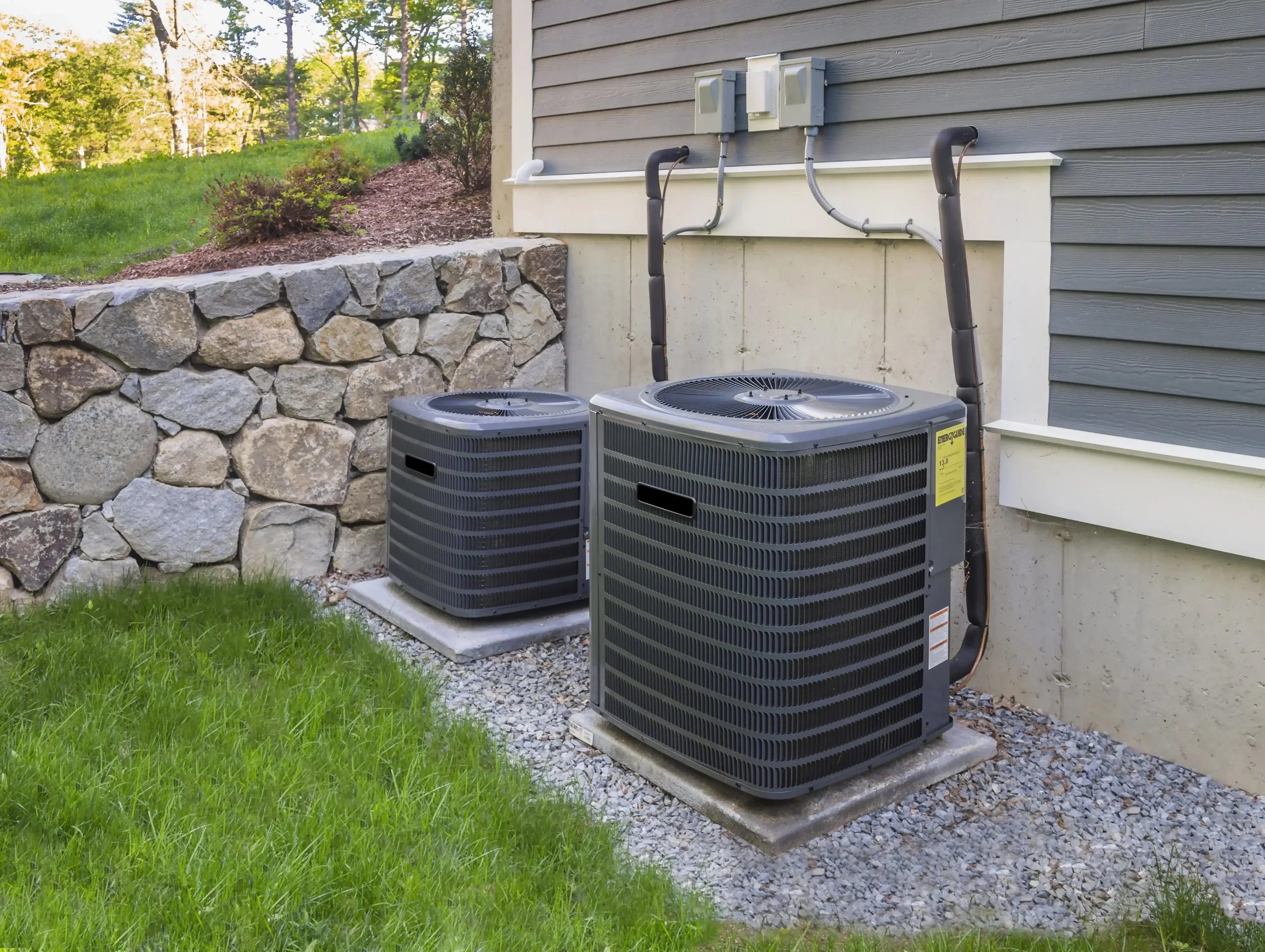 two residential air conditioning condenser units installed outside a home, representative of the HVAC equipment eligible for 2026 utility rebates