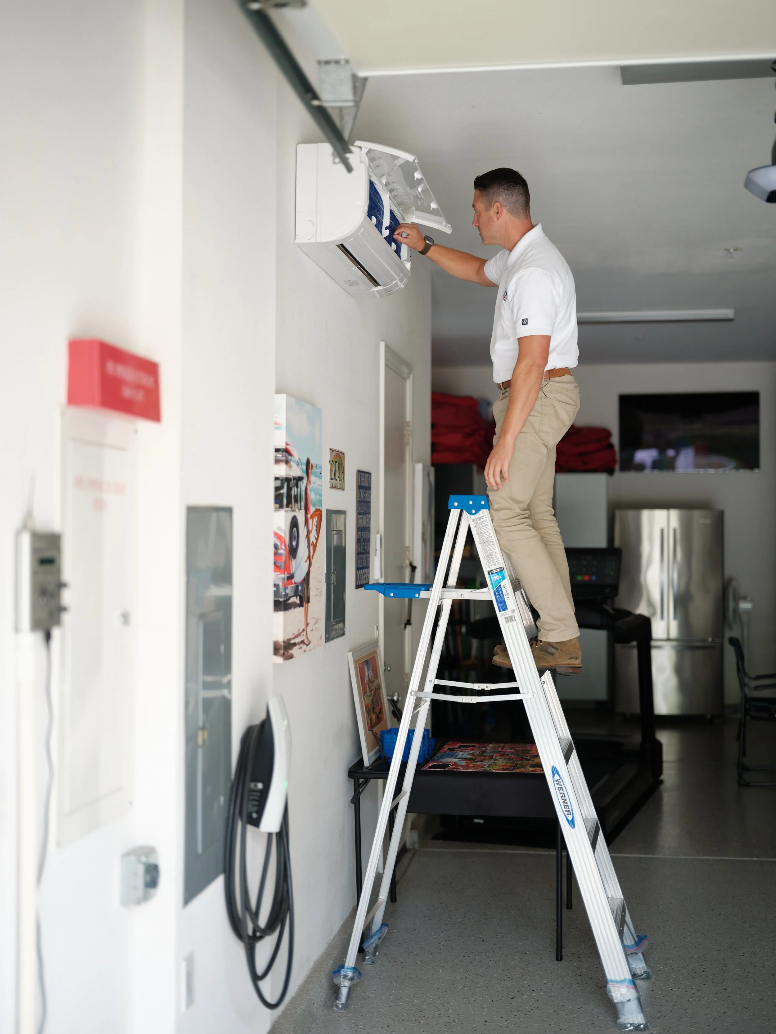 J Martin technician servicing a ductless mini-split system in a converted garage, a common solution for rooms with uneven temperatures in Orange County homes
