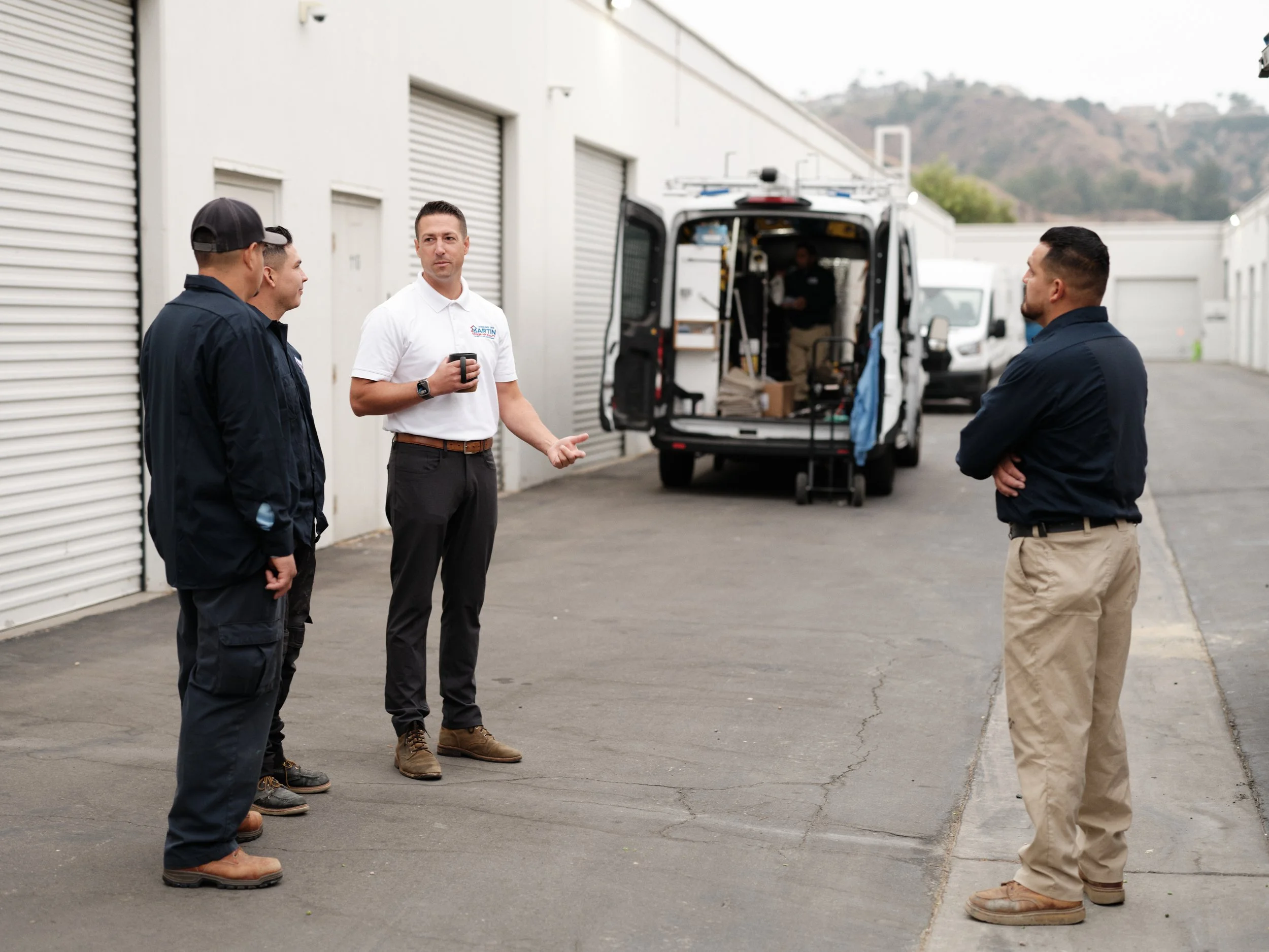 HVAC team members having morning meeting outside service facility with fully equipped work van in background