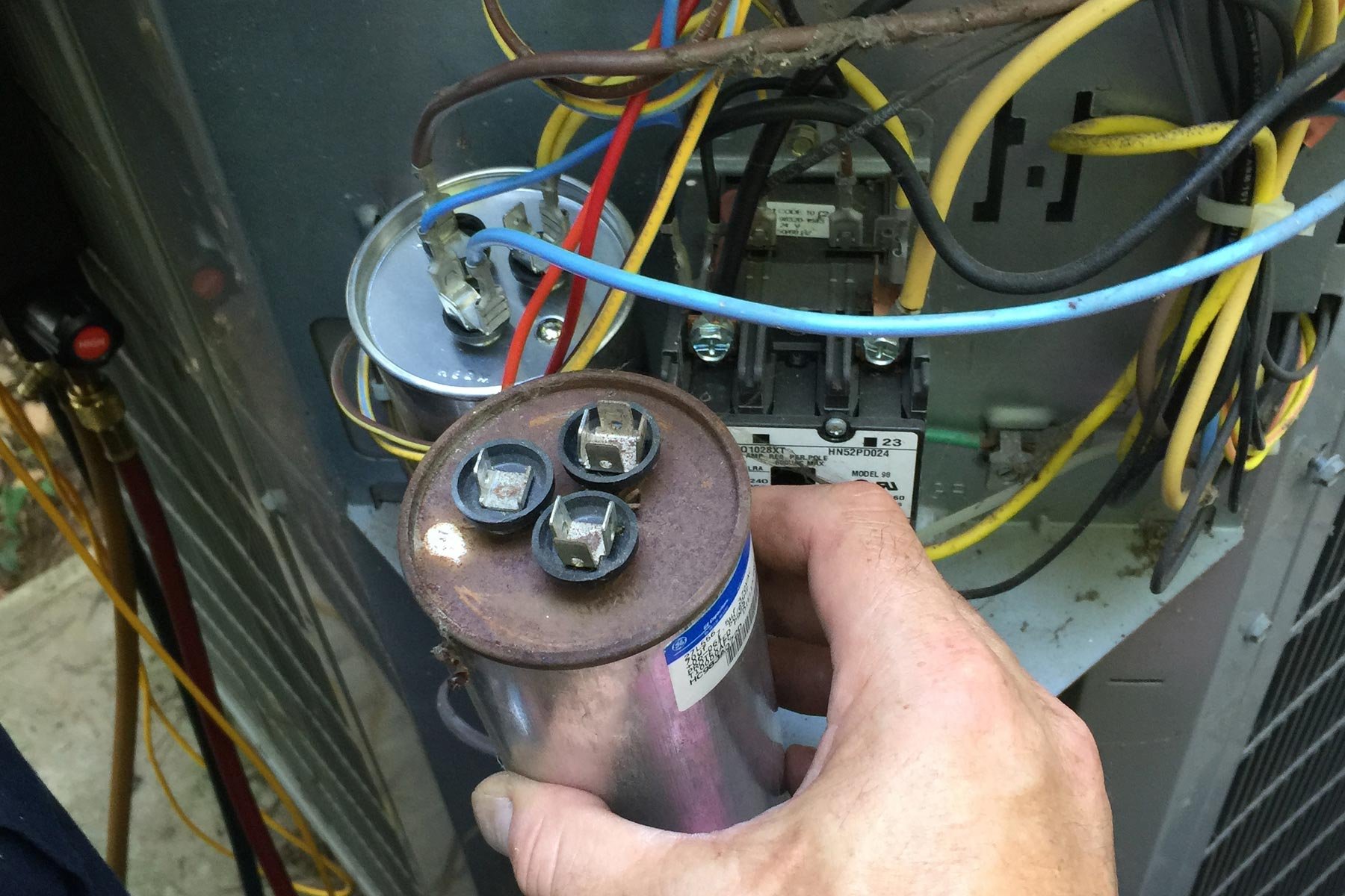 failed AC capacitor removed from an outdoor condenser unit during emergency repair in Anaheim Hills