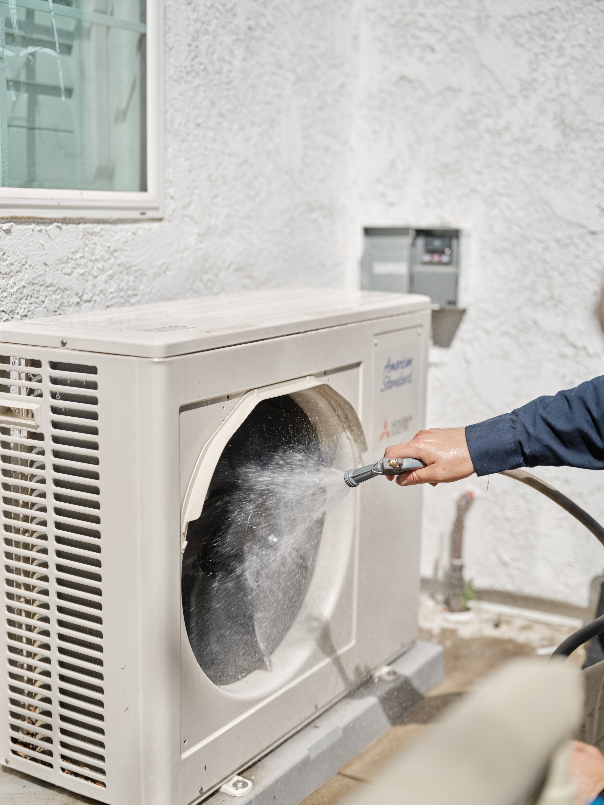 HVAC technician cleaning AC condenser coils during maintenance service in Rancho Santa Margarita Orange County